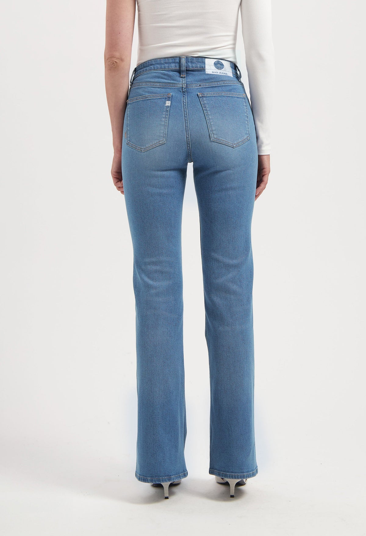 Back view of a person wearing MUD Jeans, sustainable blue denim with a straight-leg fit, paired with a simple white top.