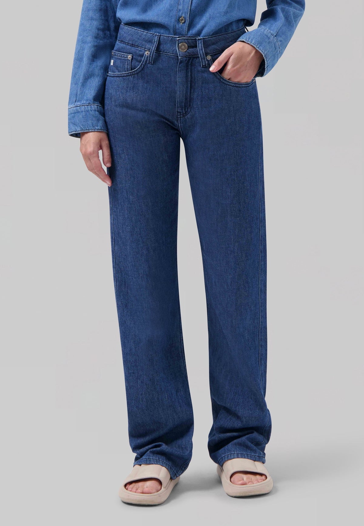 Wide-leg blue denim jeans paired with matching blue denim shirt and beige slip-on sandals, showcasing a casual style.