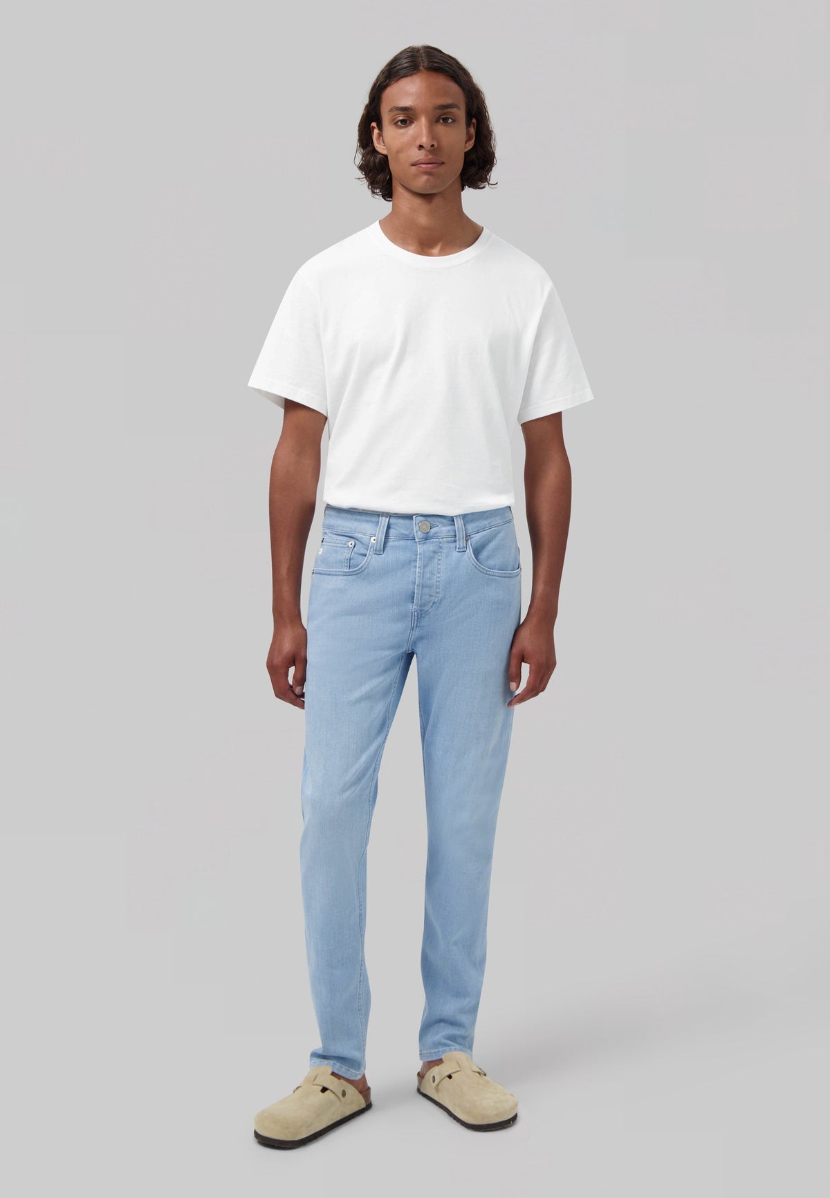 Sustainable MUD Jeans in classic blue denim, worn with a white shirt and navy sweater, showcasing ethical fashion.