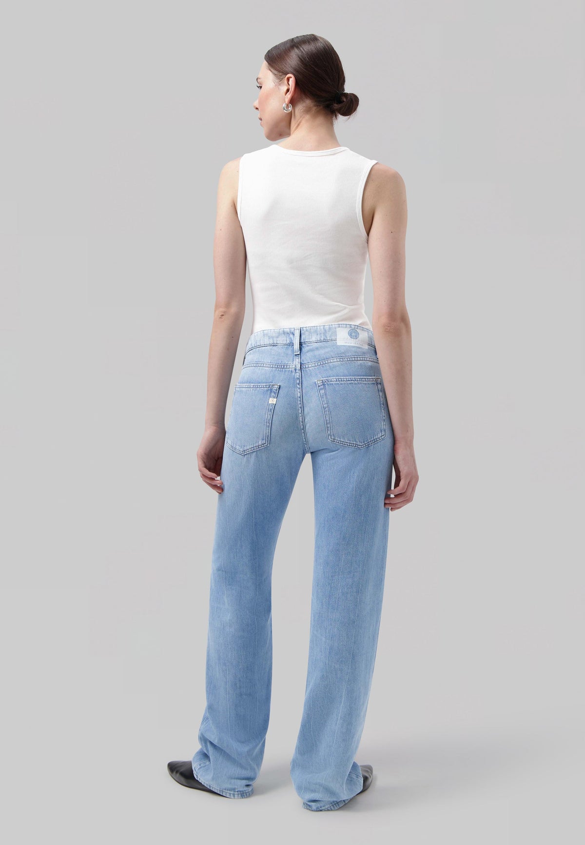Wide-leg light blue jeans in soft denim, paired with a white sleeveless top, creating a casual chic look.