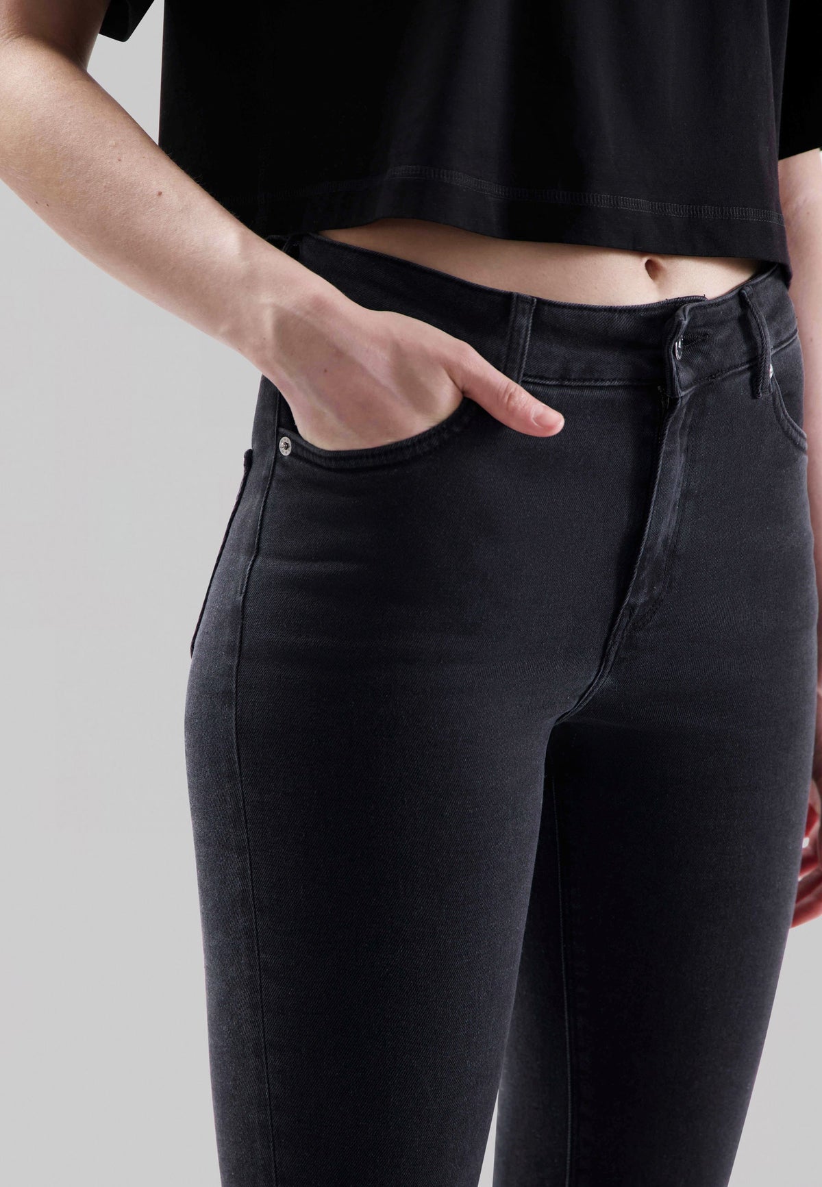 High-waisted, dark-wash skinny jeans paired with a black cropped top, highlighting a sleek, minimalist fashion style.
