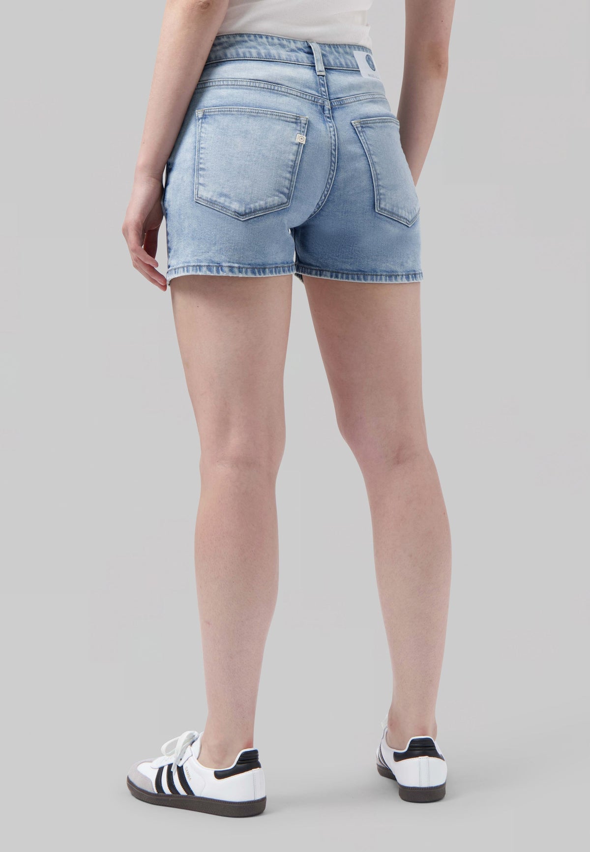High-waisted light blue denim shorts with back pockets, worn with a simple white top and casual white sneakers.