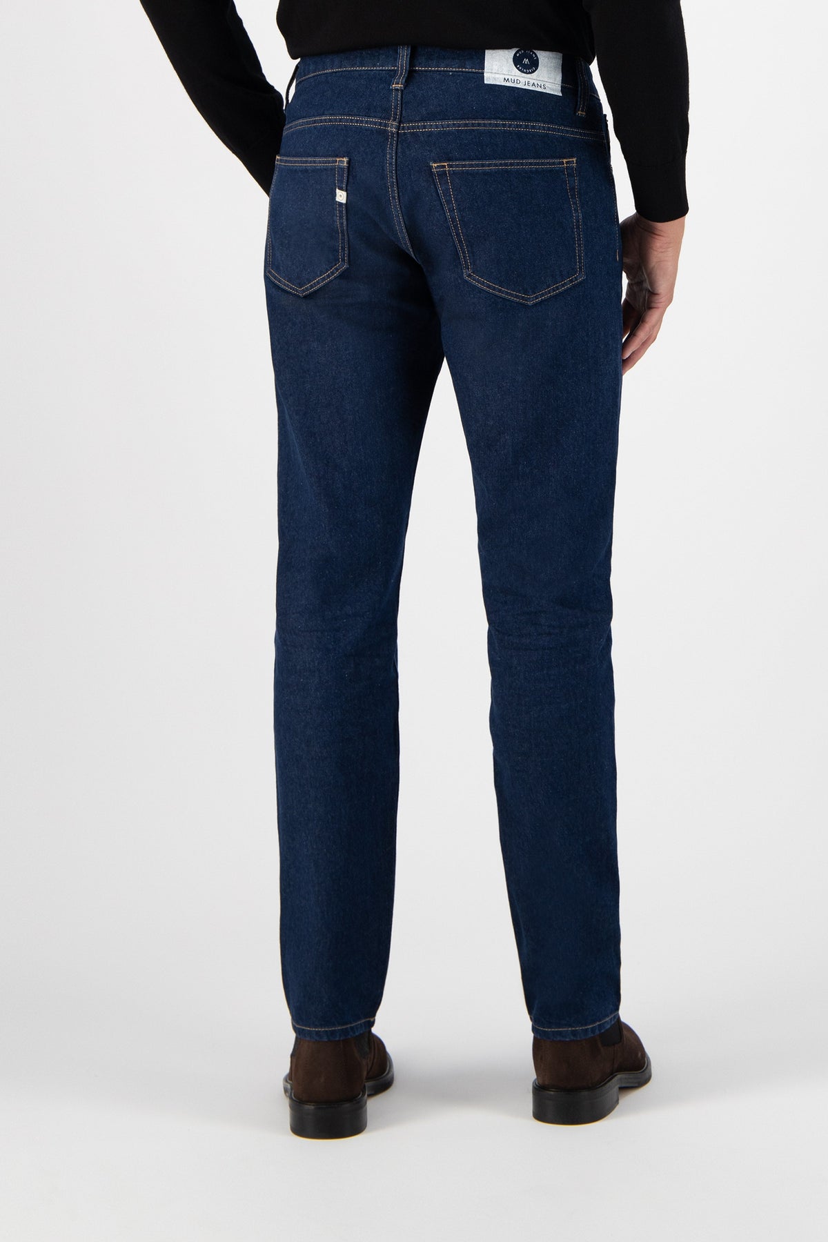 Sustainable MUD Jeans in light blue denim paired with a white tee and navy tote, emphasizing ethical fashion choices.