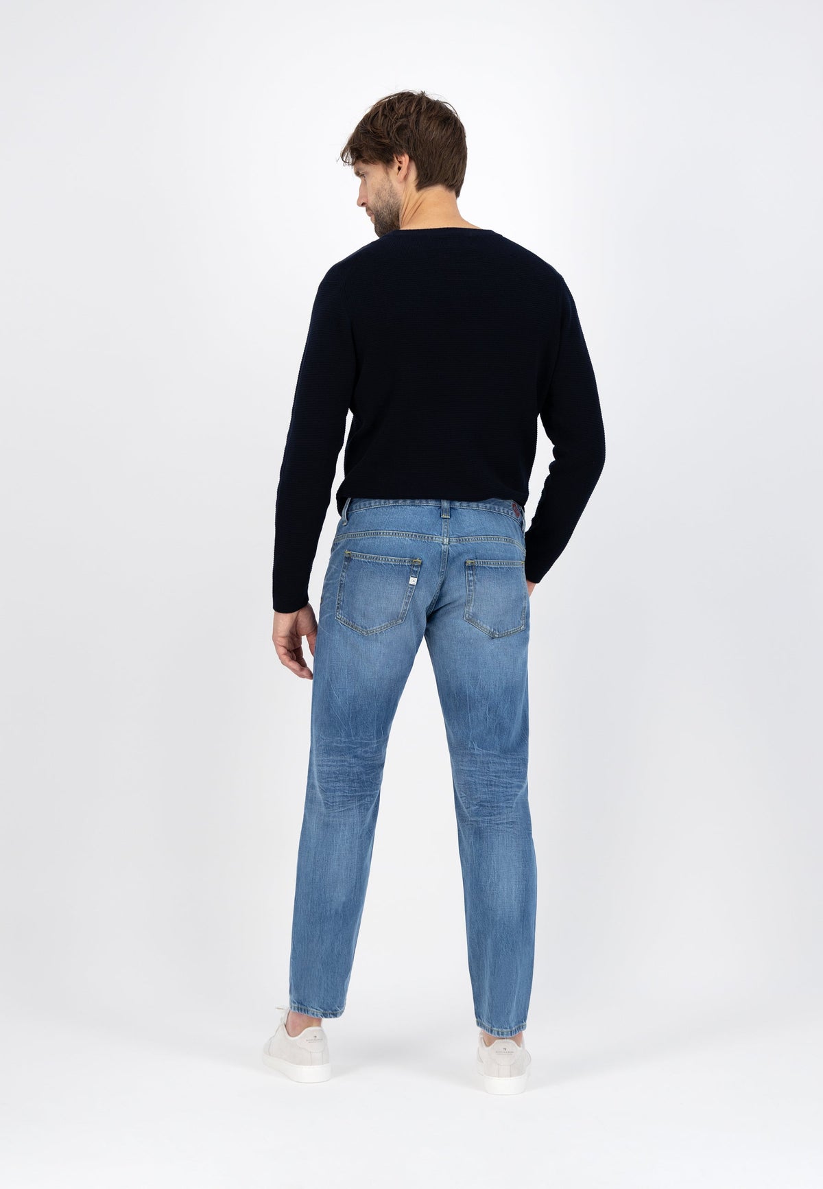 Sustainable MUD Jeans in dark denim paired with a light blue shirt, showcasing eco-friendly, ethical fashion design.