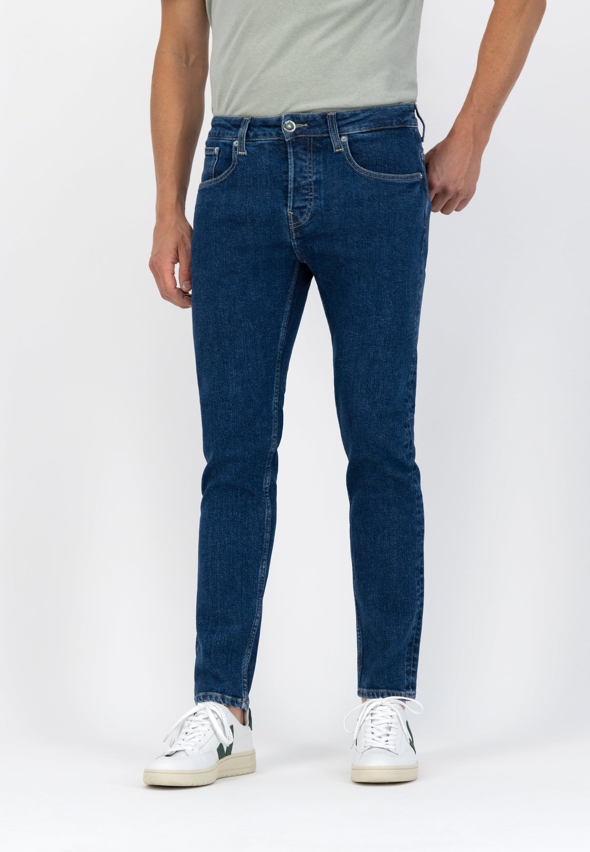Sustainable Mud Jeans in light blue denim with organic cotton, paired with a black turtleneck and beige suede boots.