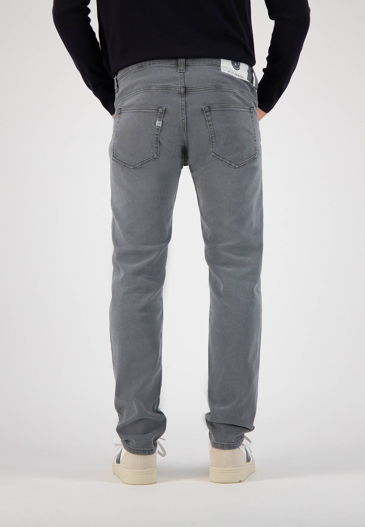 Sustainable MUD Jeans in dark blue denim, featuring a slim fit, paired with a dark navy t-shirt, promoting ethical fashion.