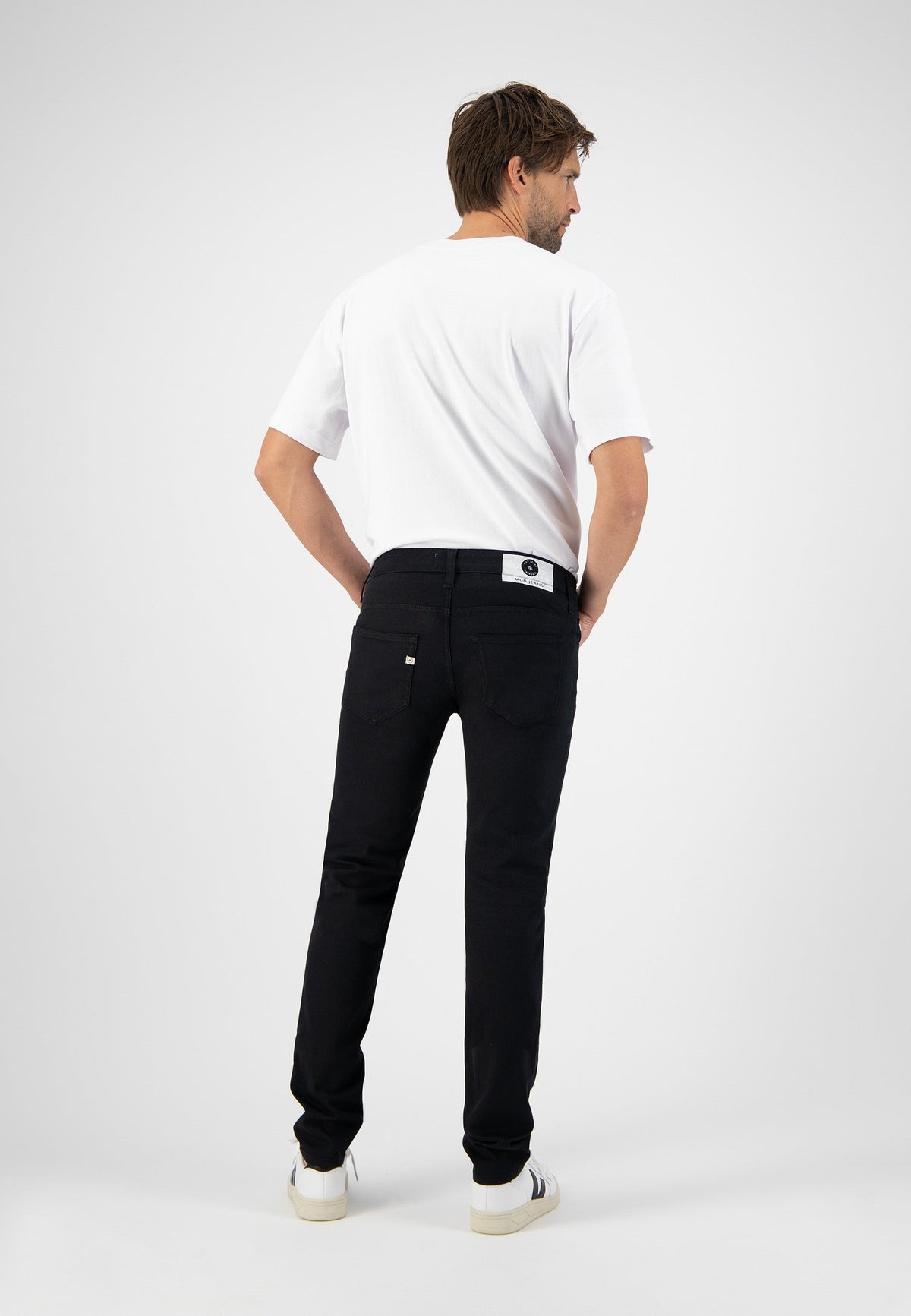 Sustainable MUD Jeans crafted from organic cotton in a sleek black finish, paired with a minimalist white tee.