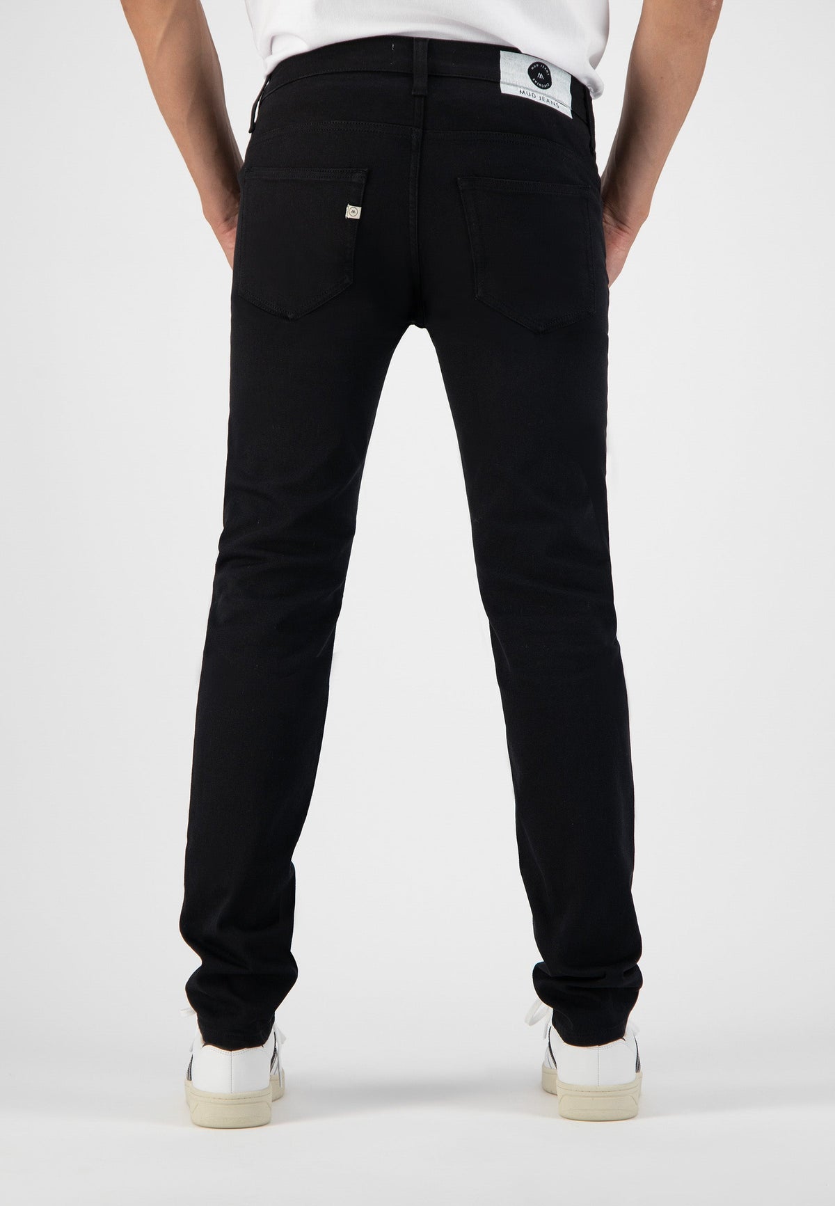 Sustainable MUD Jeans in black denim, crafted from ethical materials, shown from the back, paired with white sneakers.
