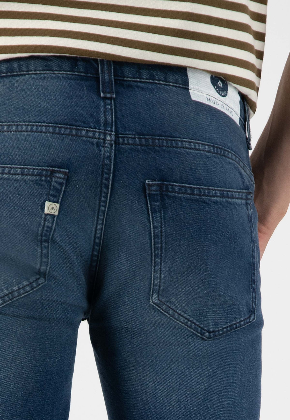 Sustainable MUD Jeans in dark blue denim, made from ethical materials, showcased with a white shirt.
