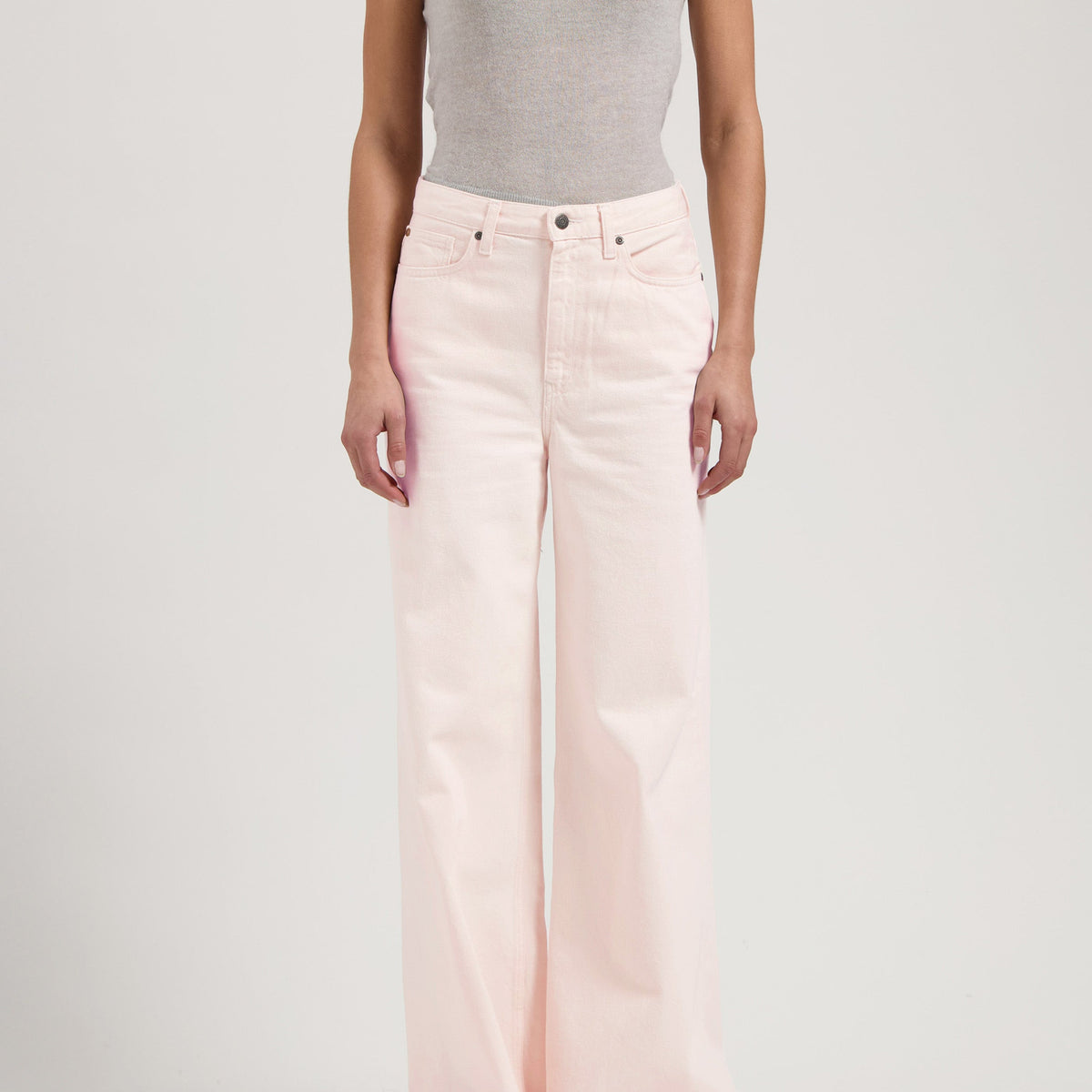 Wide-leg pale pink jeans paired with a form-fitting light gray sleeveless top, showcasing casual chic style.