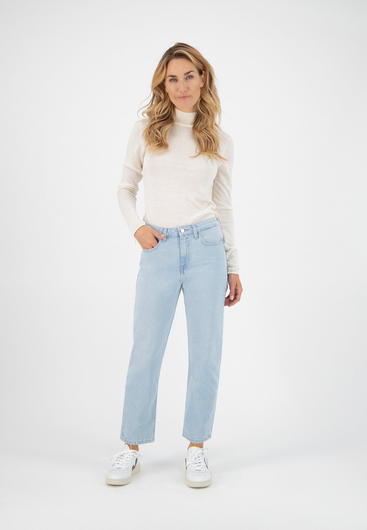 Casual outfit featuring a cream long-sleeve top paired with light blue straight-leg jeans and white sneakers.