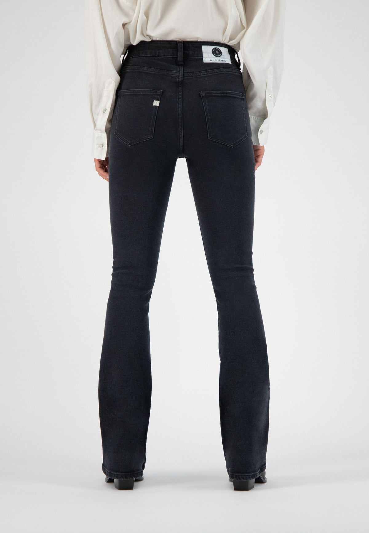 High-waisted black denim jeans by MUD, featuring a flattering fit, visible back pockets, worn with a classic white shirt.