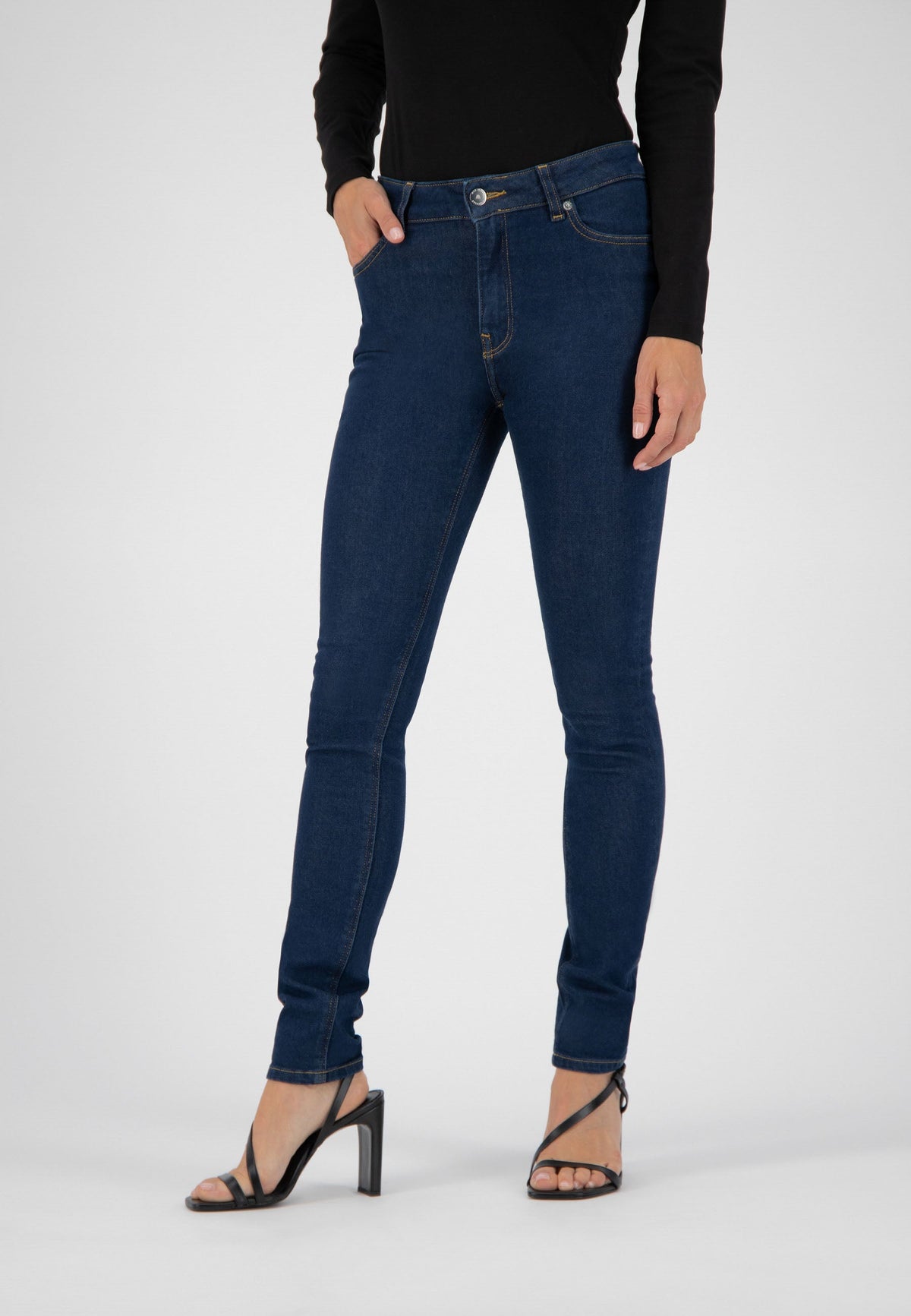 Dark blue skinny jeans paired with a fitted black long-sleeve top and black strappy high heels.