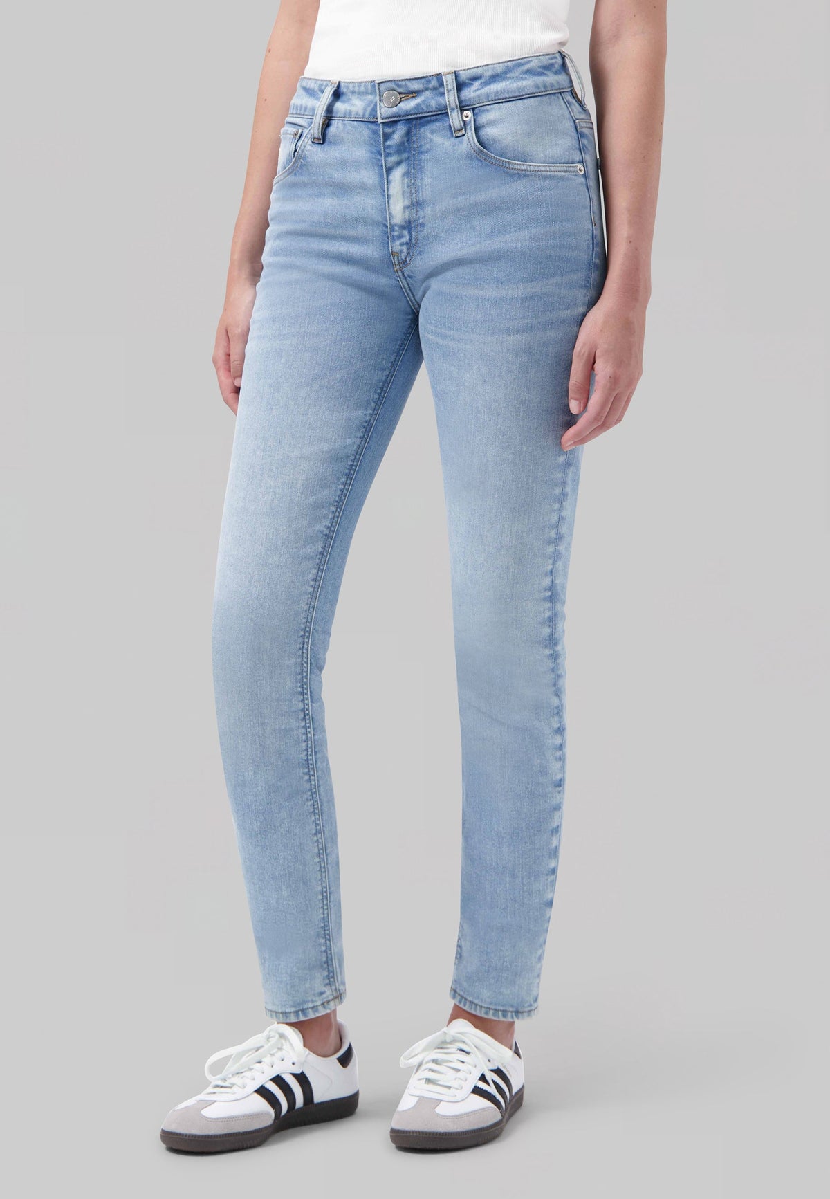 Light blue, slim-fit denim jeans worn with a white top and white sneakers, showcasing casual and trendy style.
