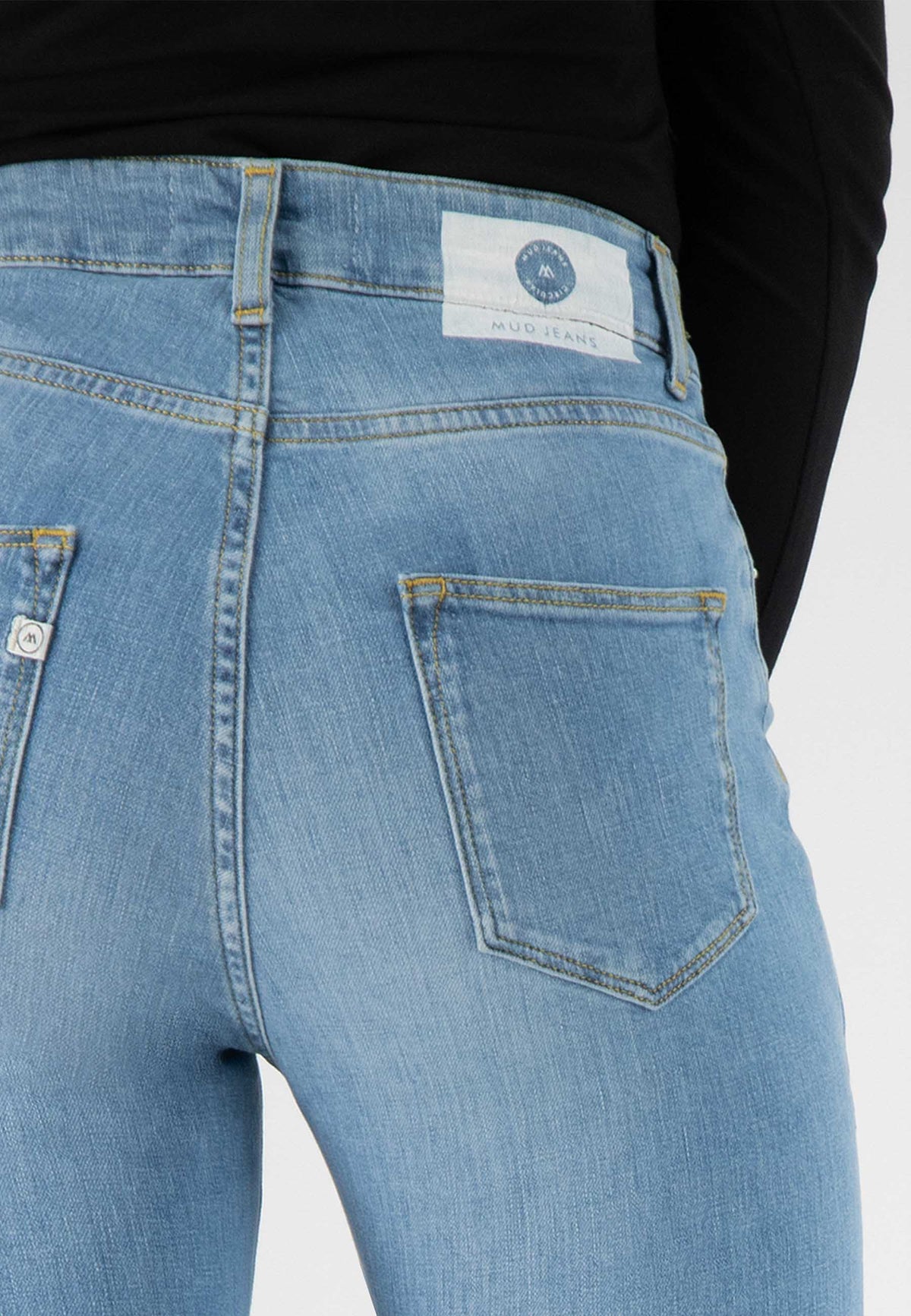 Light blue MUD Jeans made from sustainable materials, featuring a high-waist design with a visible back pocket.