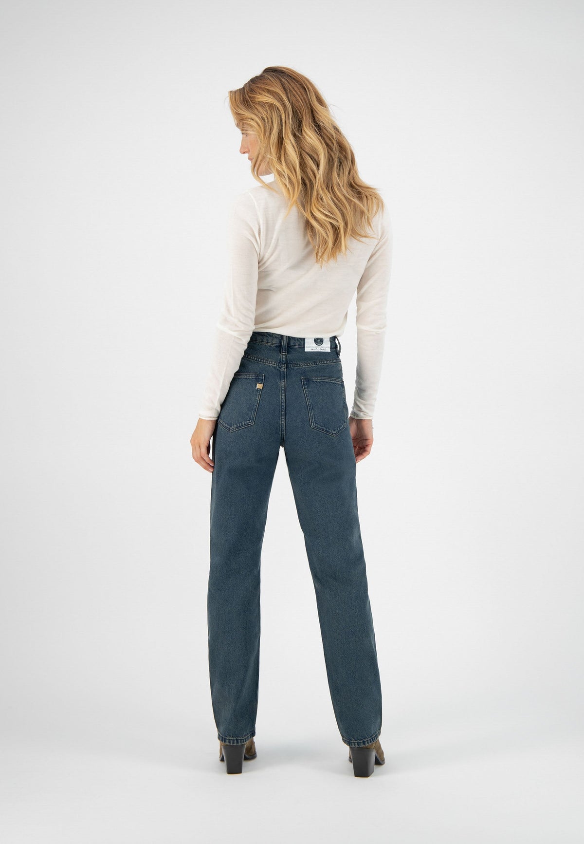 Model wearing classic blue high-waisted jeans paired with a white fitted long-sleeve top, showcasing relaxed style.