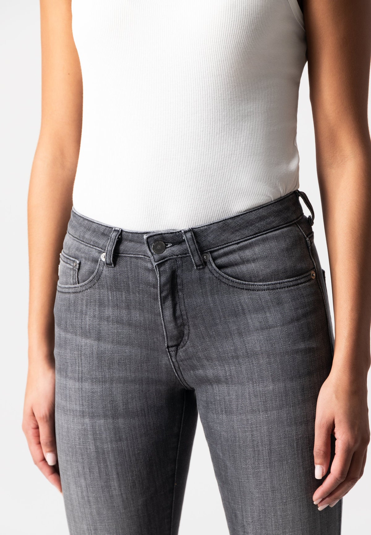 Gray slim-fit jeans paired with a white ribbed tank top, showcasing a modern casual style for women’s fashion.