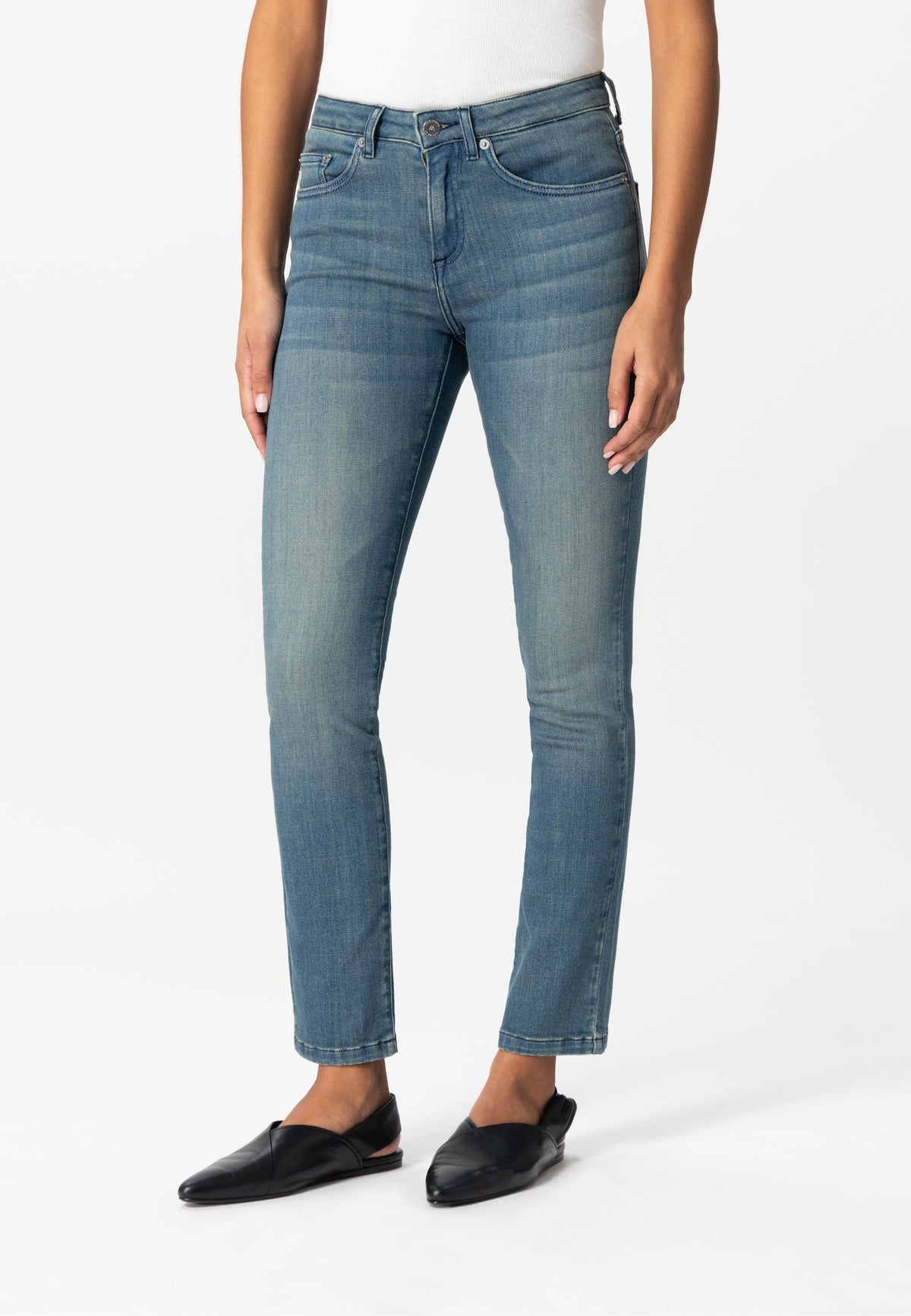 Straight-leg blue denim jeans styled with black flats and a white top, showcasing a classic casual look.