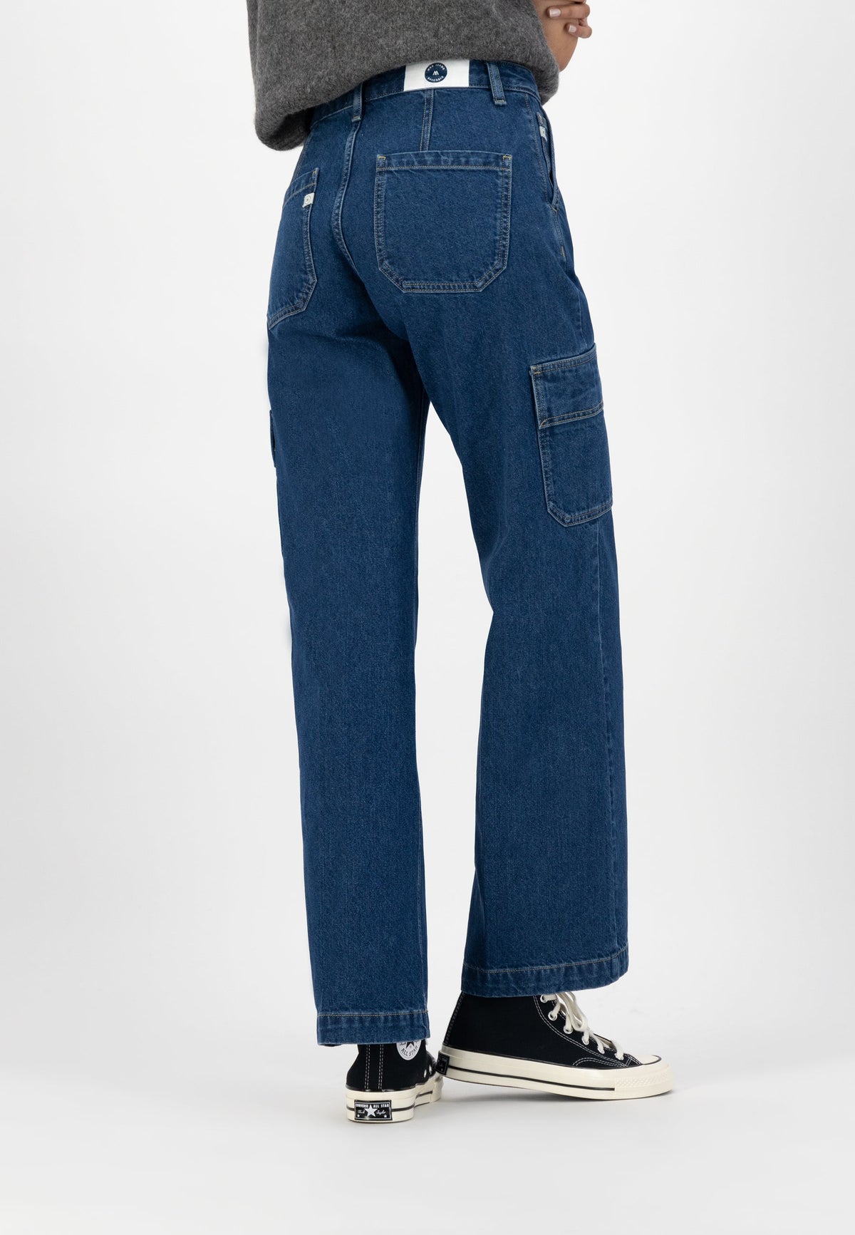 Dark blue cargo jeans with a relaxed fit, featuring multiple pockets, paired with black high-top sneakers and a gray sweater.