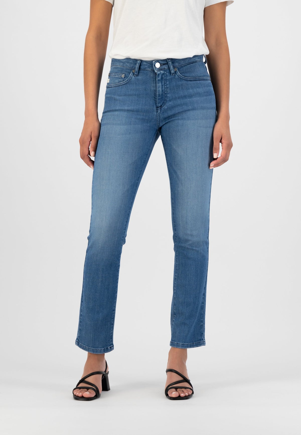 Blue straight-leg jeans paired with a white tee and black strappy heels, showing casual chic style.