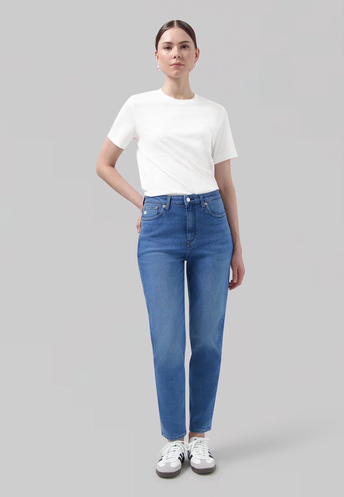 Casual outfit featuring a white short-sleeve T-shirt and blue high-waisted jeans paired with retro-style sneakers.