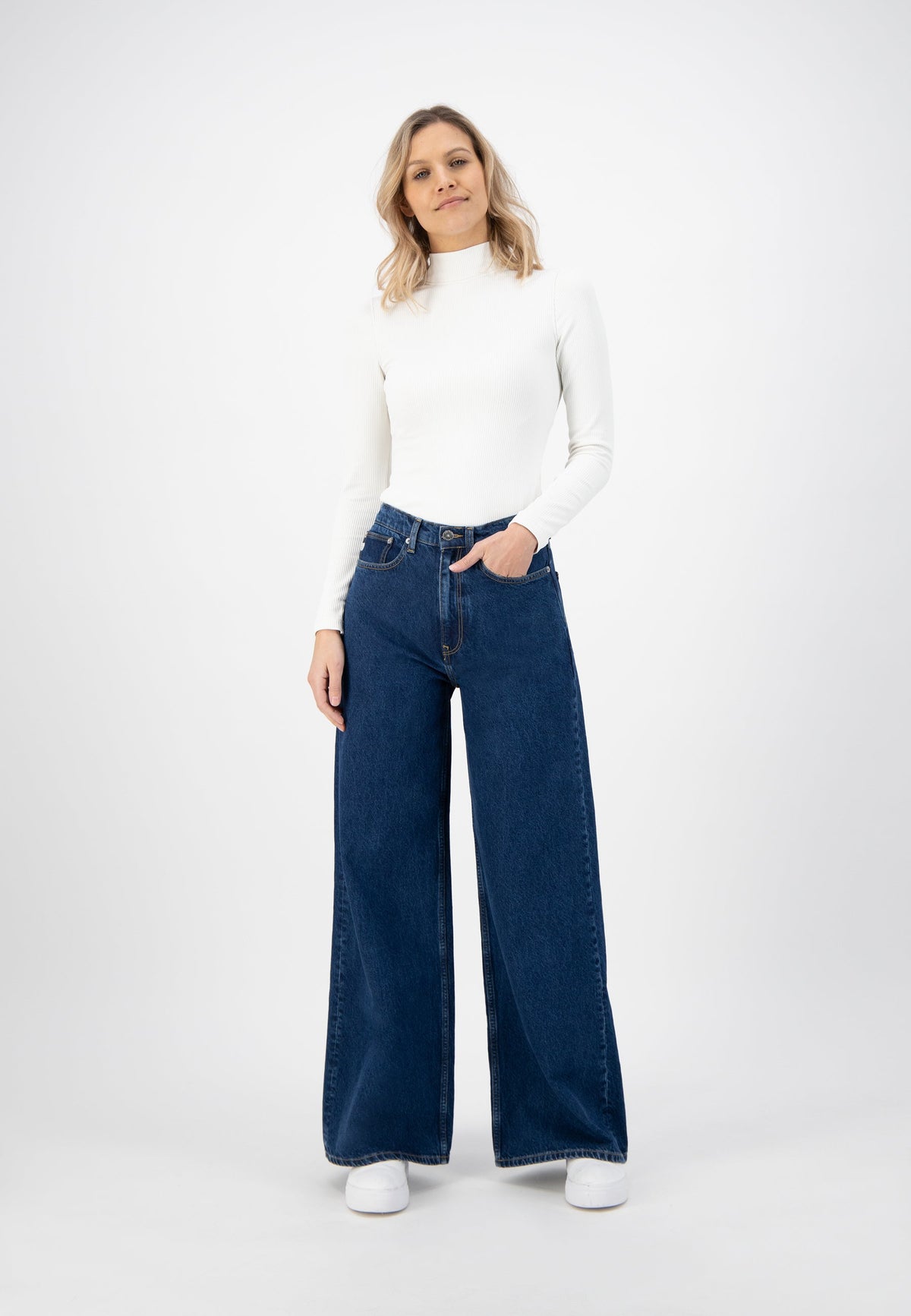 Wide-leg blue denim jeans paired with a white turtleneck sweater, showcasing a casual and chic fashion style.