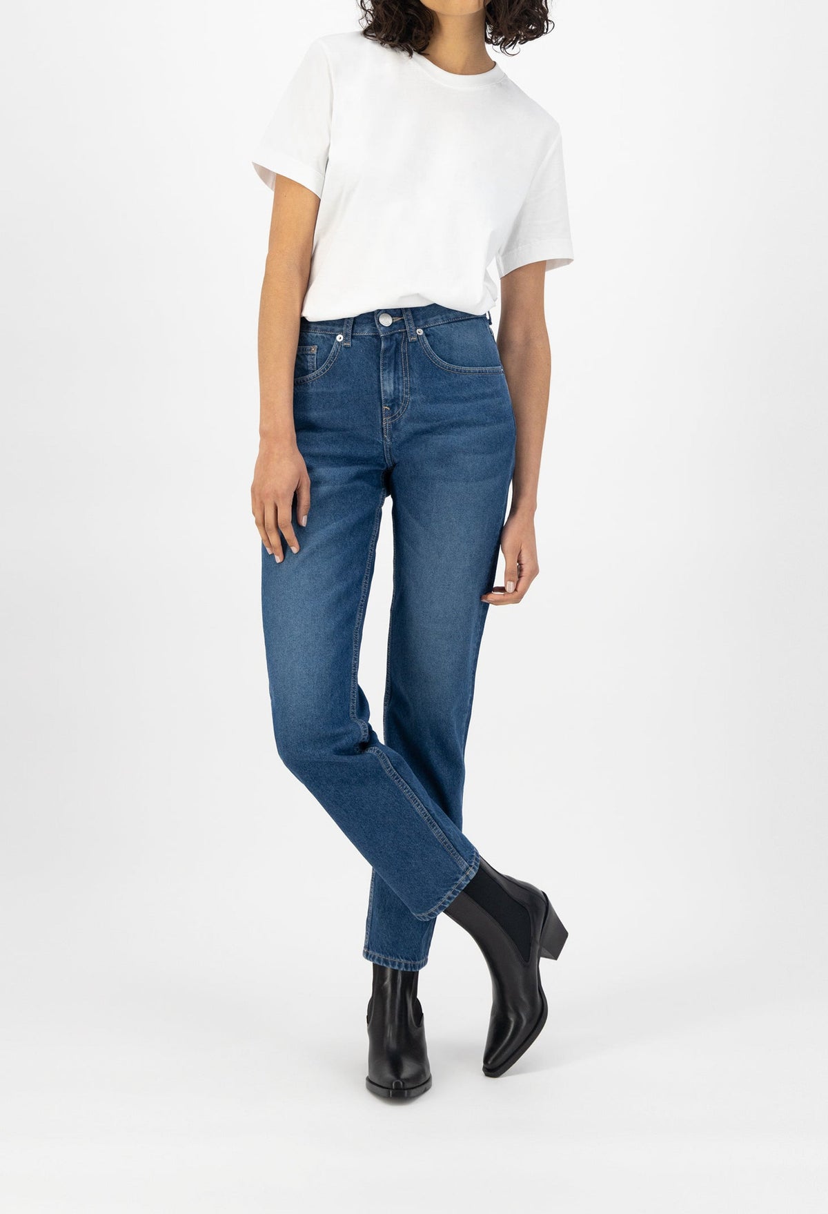Casual outfit with a white T-shirt and blue denim jeans paired with black ankle boots, showcasing a relaxed fashion style.