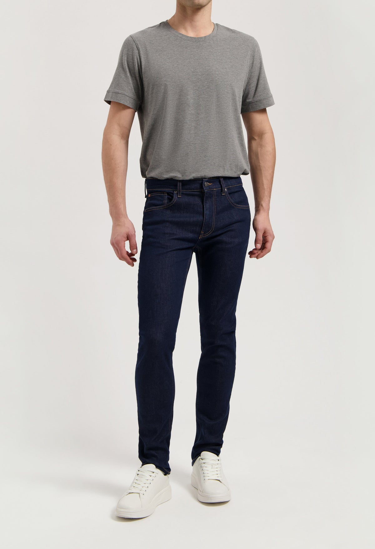 Sustainable MUD Jeans blue denim shorts styled with a white T-shirt and white sneakers for a casual look.