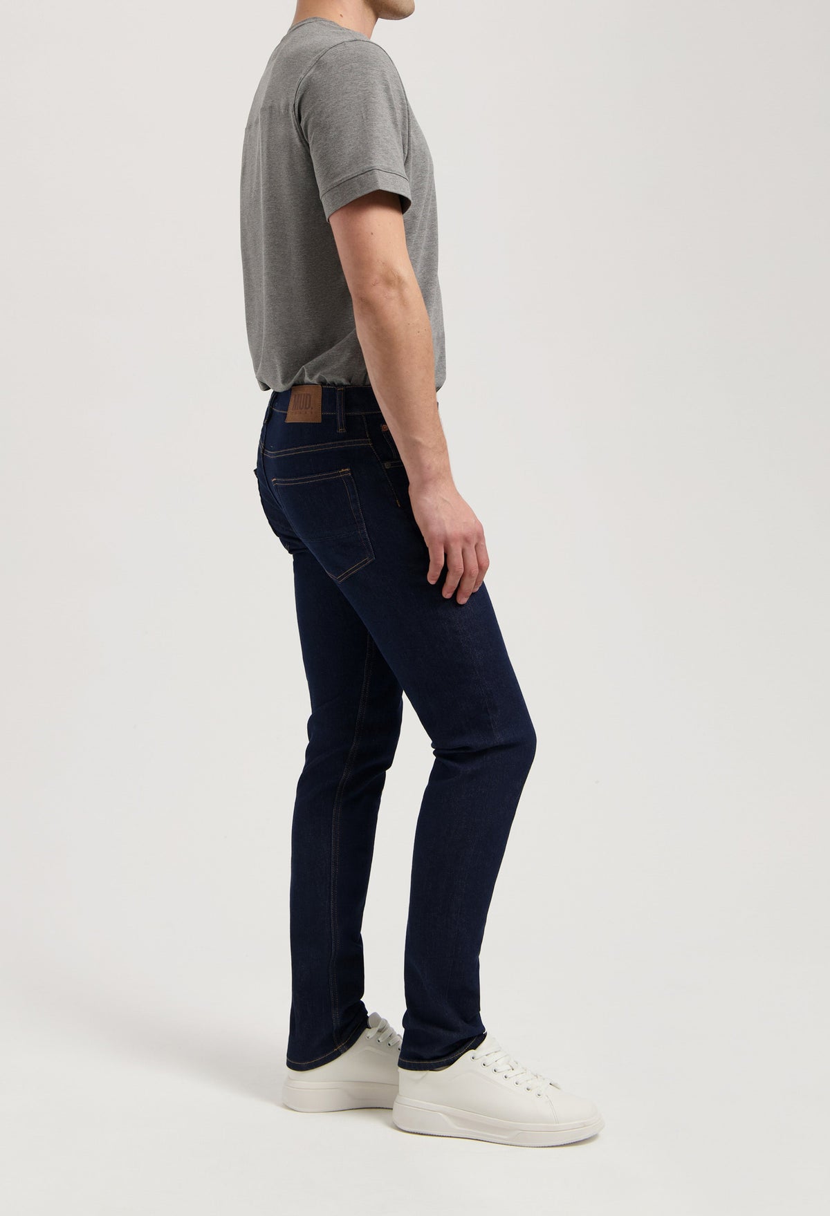 Sustainable MUD Jeans dark blue denim shorts, crafted ethically with organic cotton, paired with a white t-shirt and sneakers.
