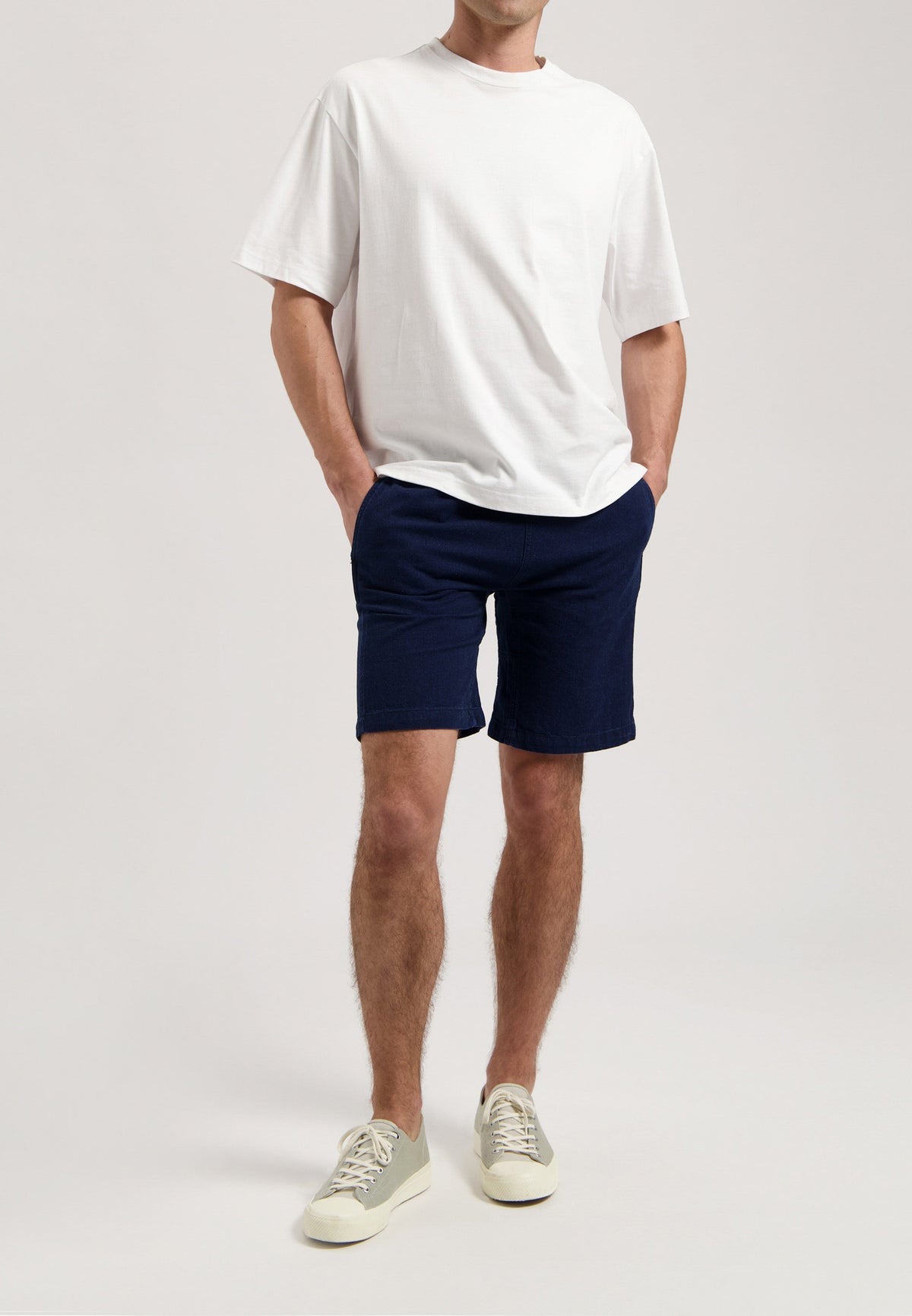 Sustainable MUD Jeans in light blue denim, classic fit, crafted from organic cotton, paired with a white shirt and sneakers.