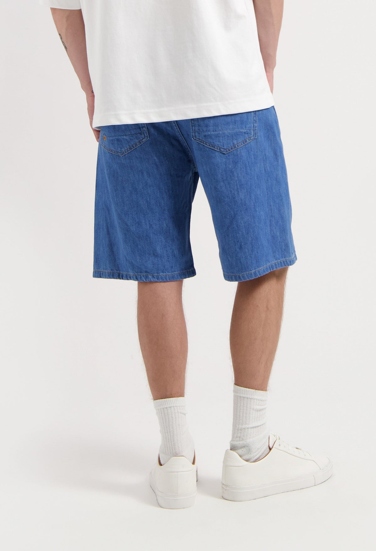 Sustainable MUD Jeans made from organic cotton, featuring mid-blue denim in a classic fit, paired with a black t-shirt.