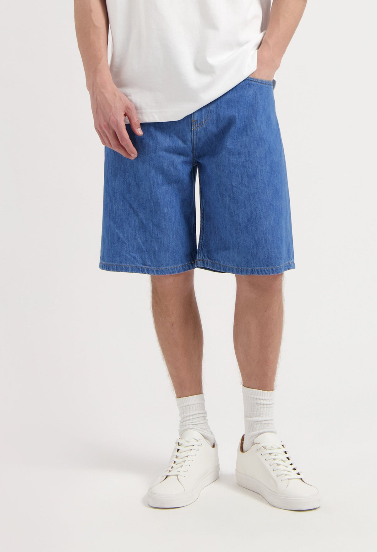 Sustainable MUD Jeans in classic blue denim, crafted from organic cotton, paired with a simple black T-shirt.