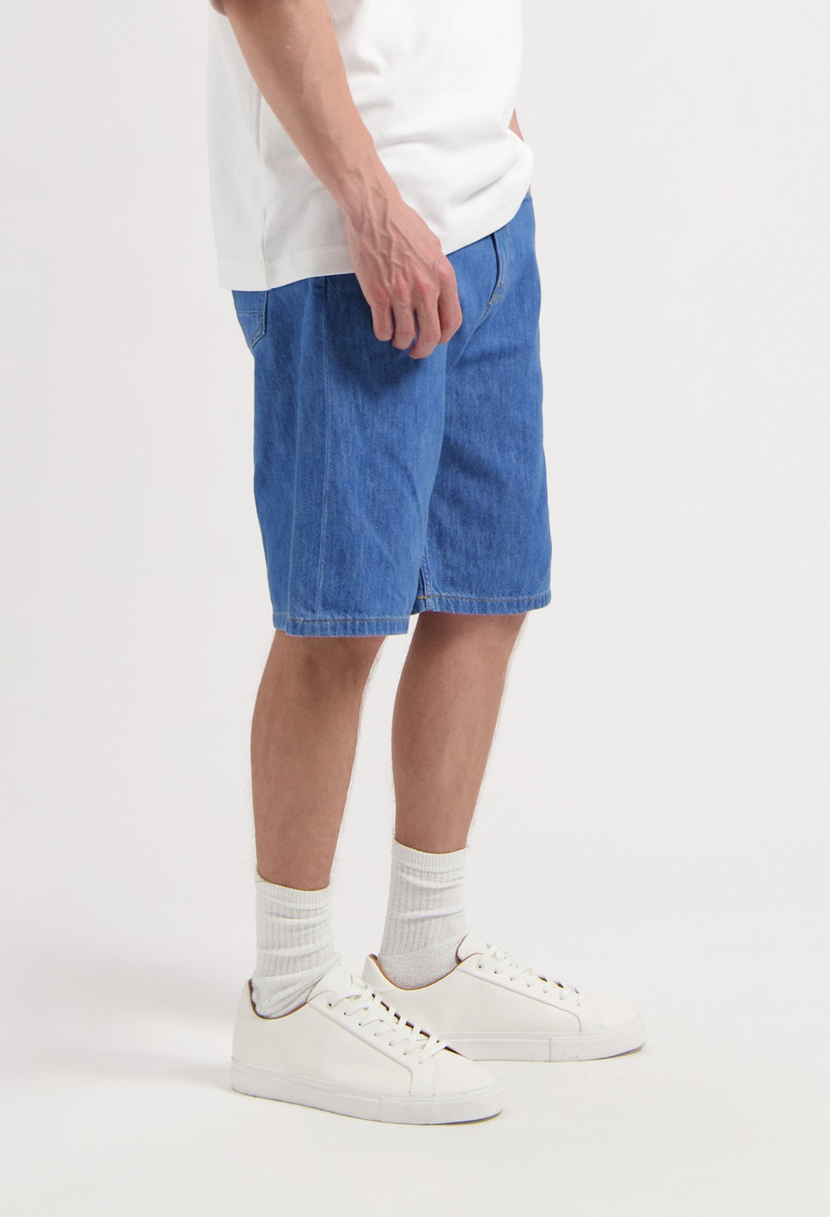 Sustainable MUD Jeans in classic blue denim, crafted ethically, paired with a black T-shirt and sneakers.