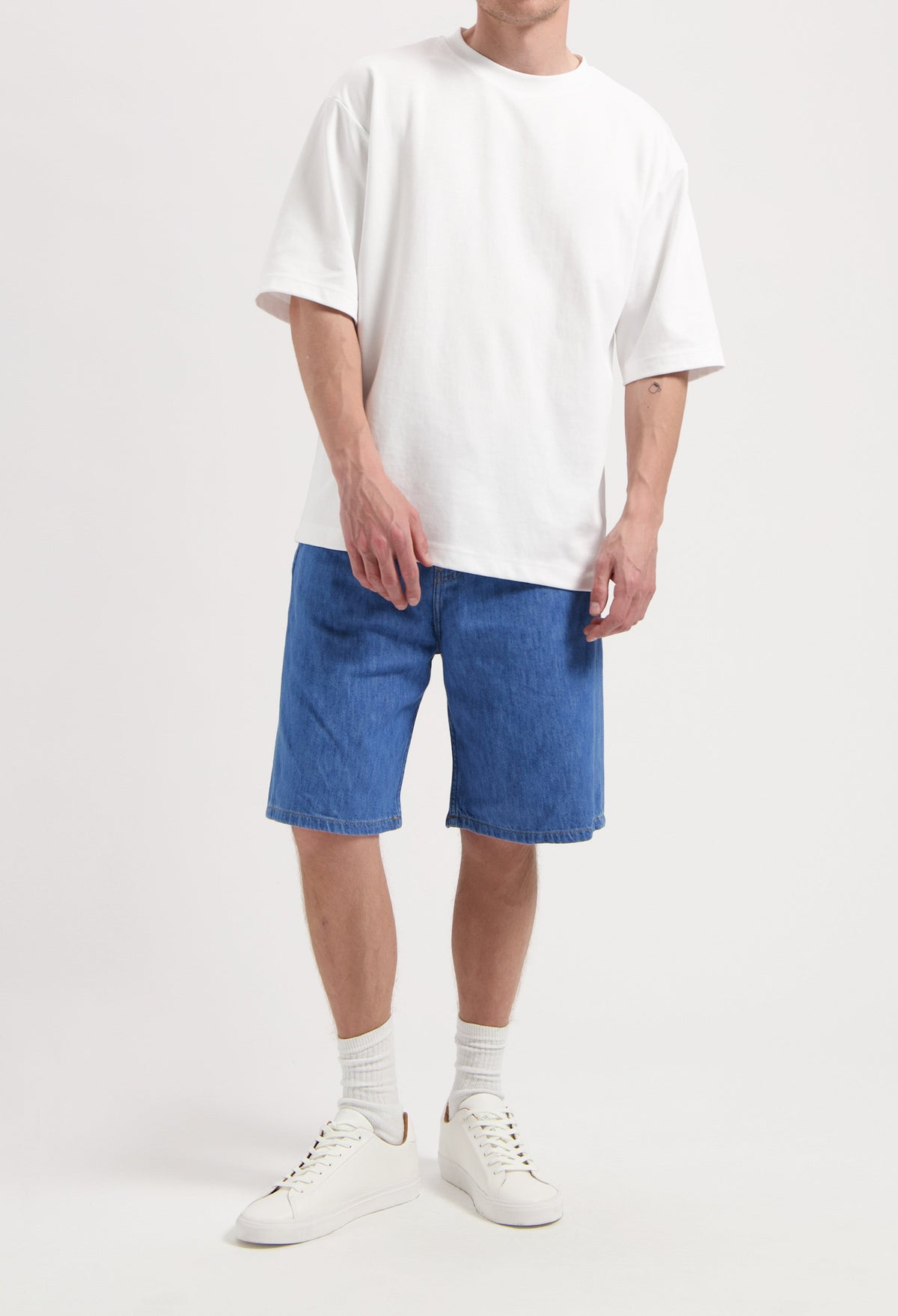 Sustainable MUD Jeans in dark blue denim, crafted ethically for casual wear, paired with white sneakers and a white T-shirt.
