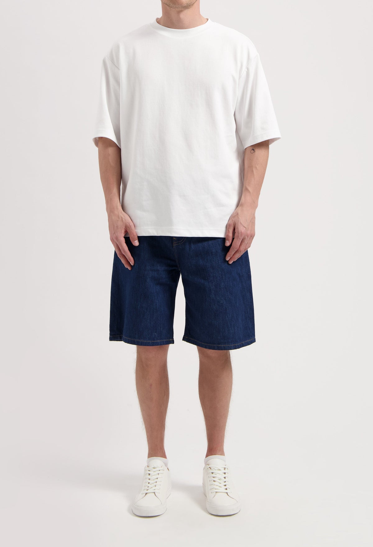 Sustainable MUD Jeans made from organic cotton in a light blue wash, paired with a gray t-shirt and black sneakers.