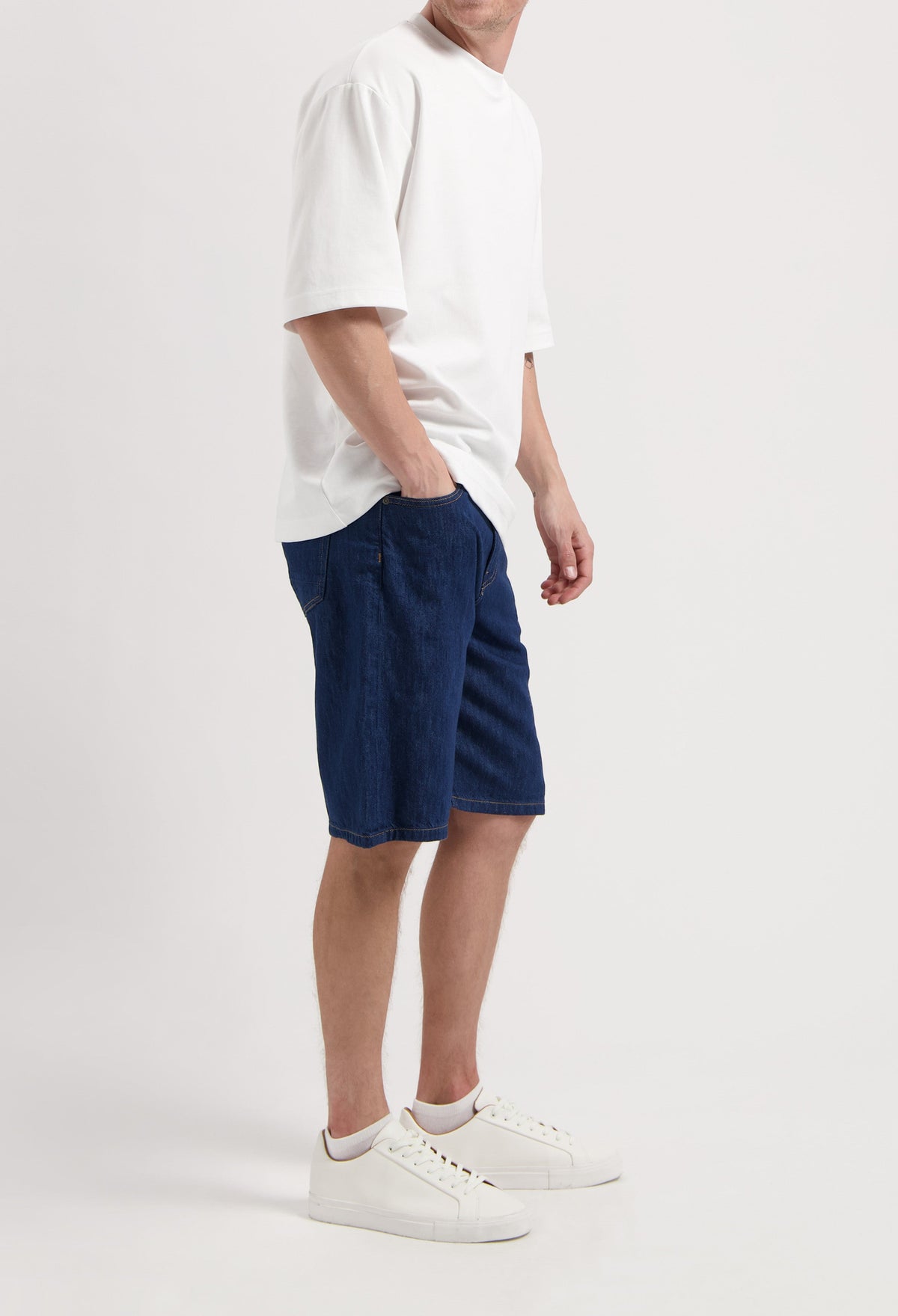 Sustainable MUD Jeans in light blue denim, classic fit, paired with a gray t-shirt and sneakers, emphasizing ethical fashion.
