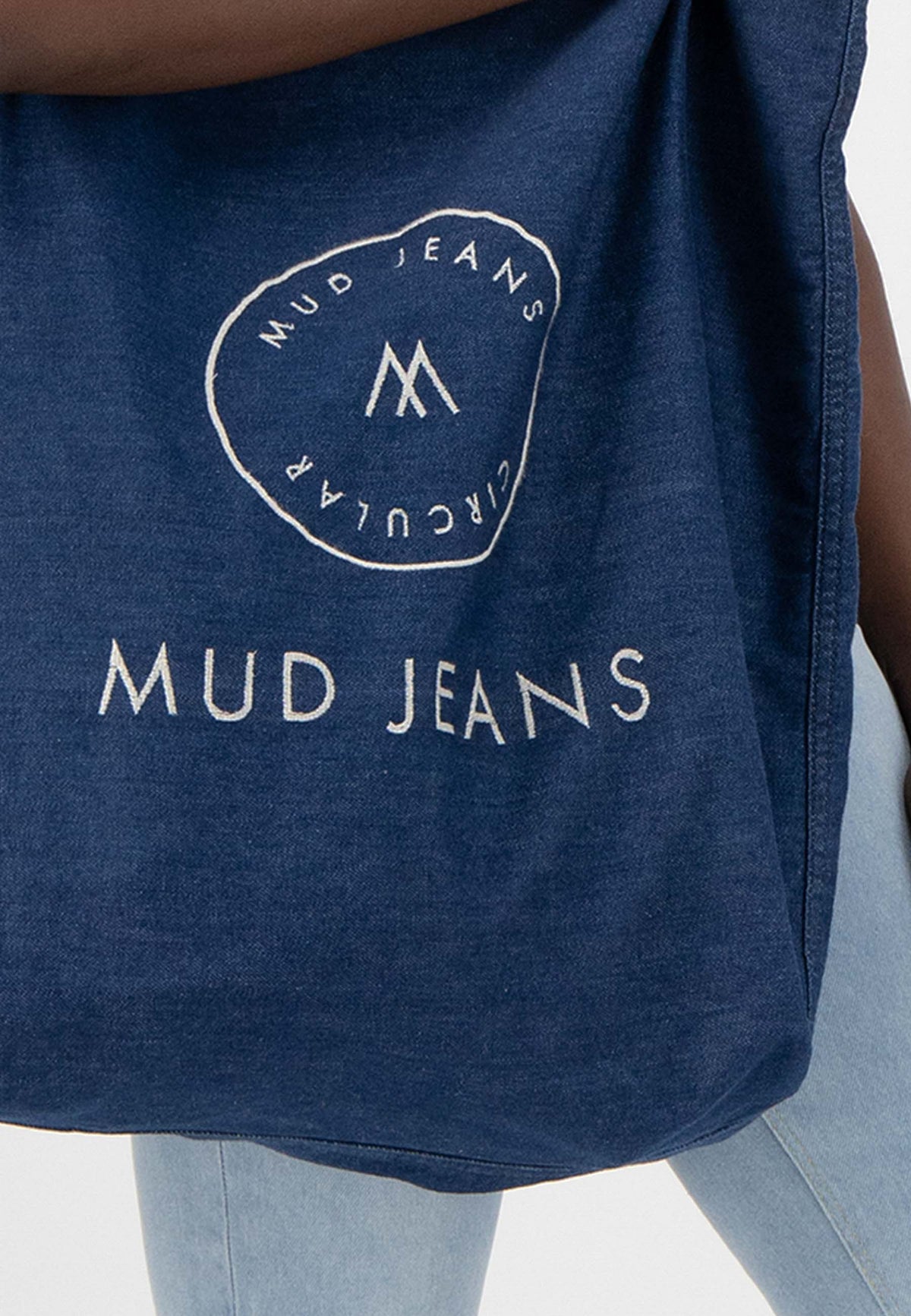 Sustainable MUD Jeans set featuring navy denim jacket and cargo pants, highlighting ethical fashion with black boots.