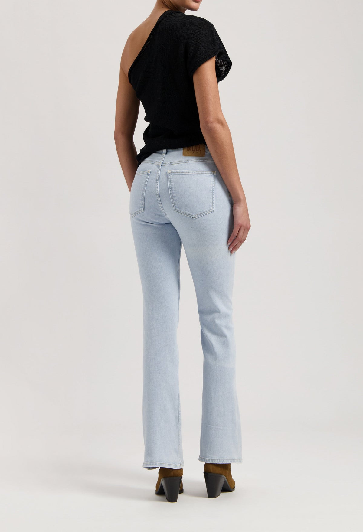 A stylish black off-shoulder top paired with light blue bootcut jeans, showcasing modern casual fashion.