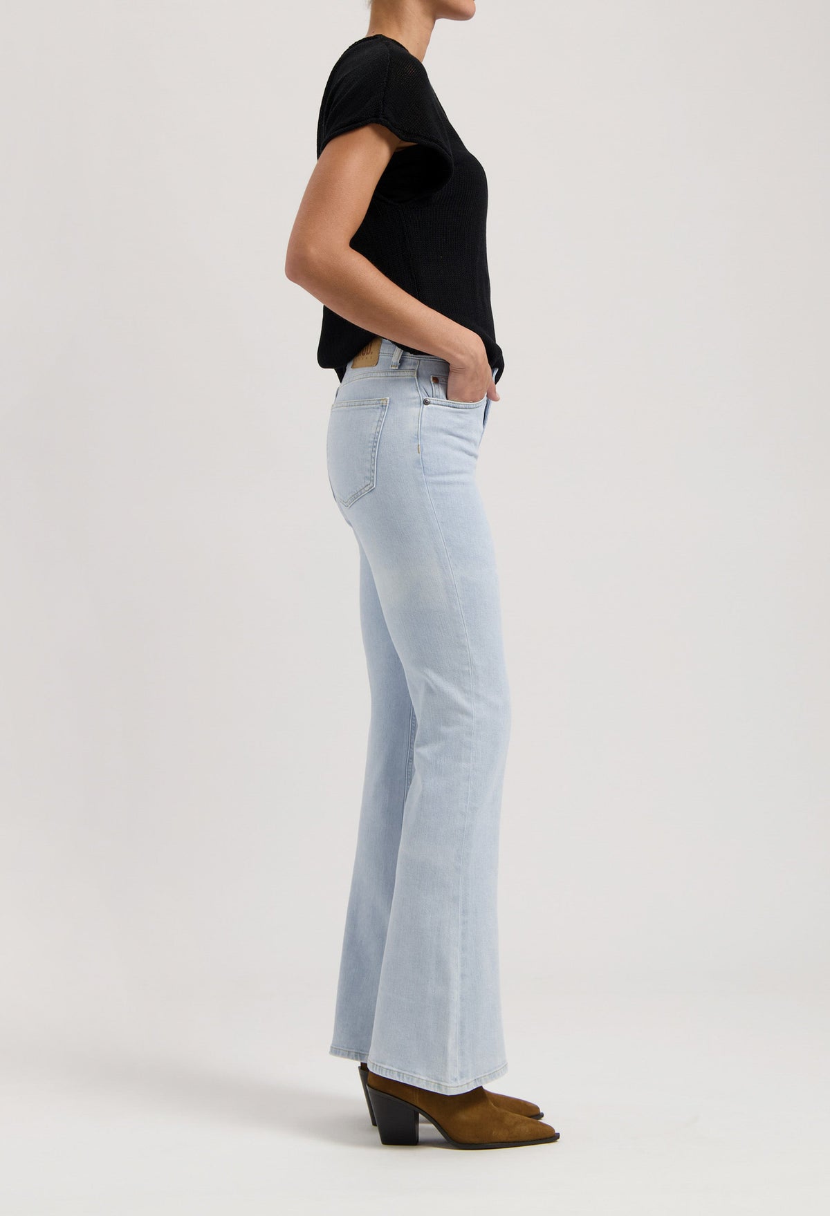 Light blue bootcut jeans paired with a fitted black T-shirt and brown suede ankle boots, showcasing a modern casual look.
