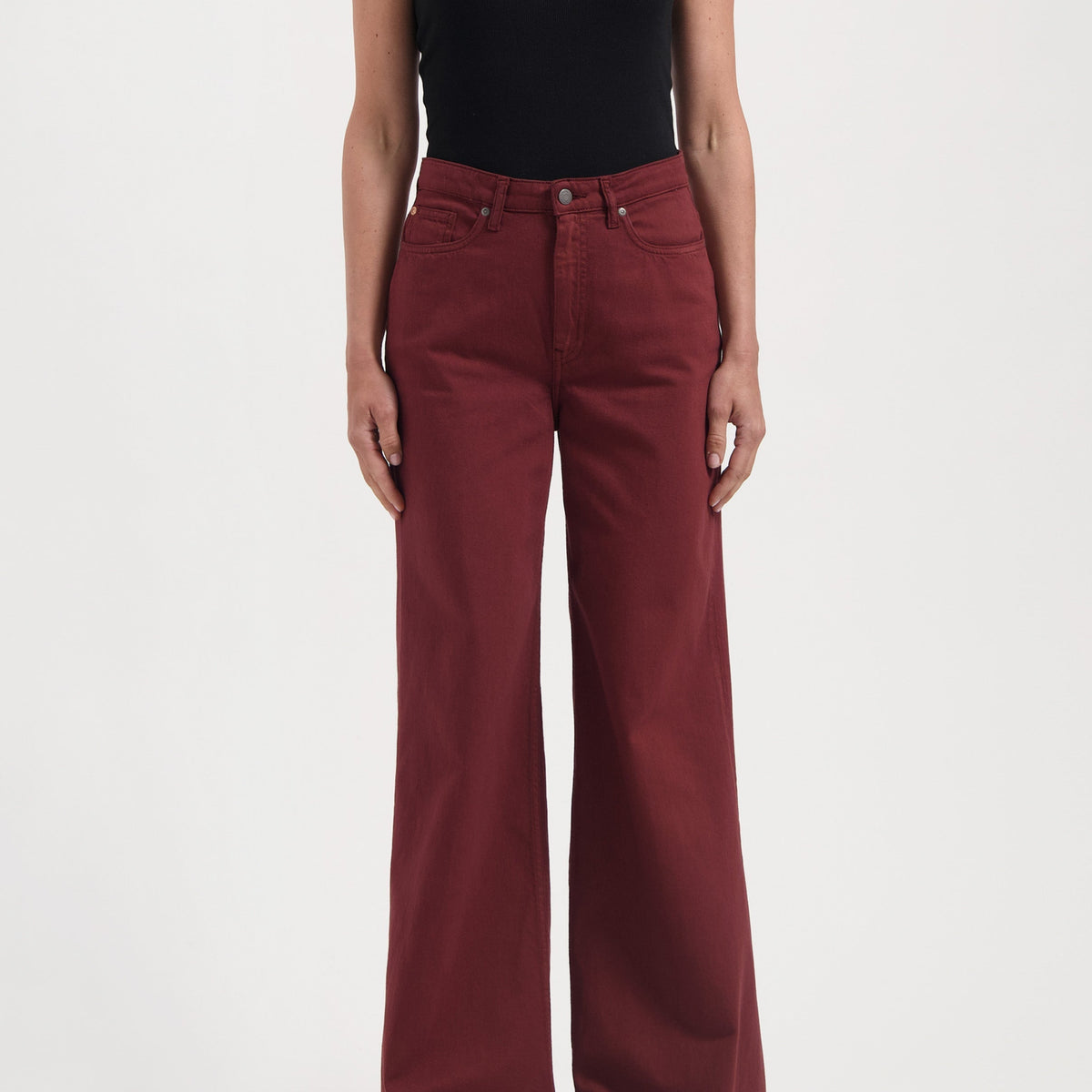 Wide-leg burgundy cotton pants with high waist, paired with a black one-shoulder top, showcasing modern casual style.
