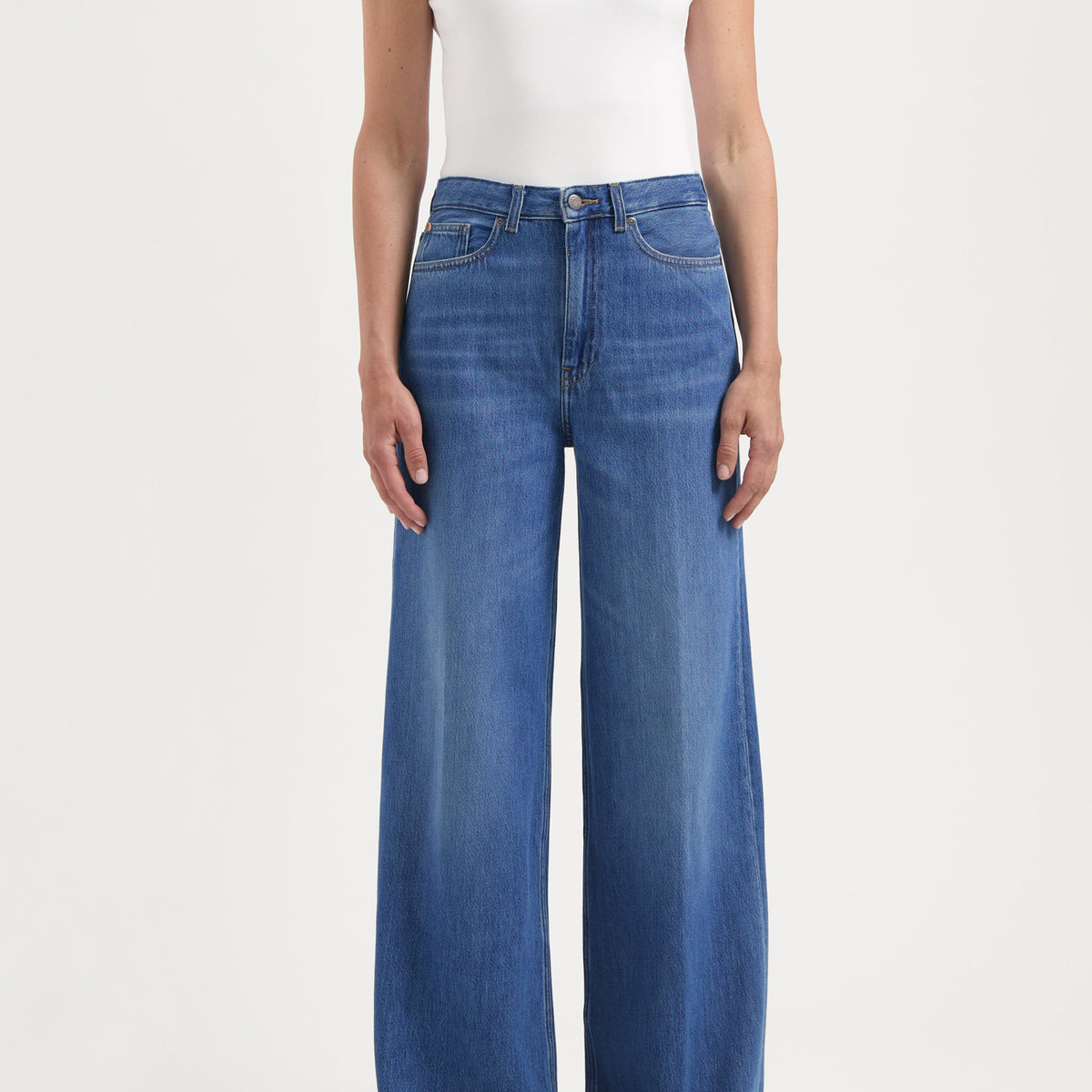 Wide-leg blue denim jeans paired with a white sleeveless top, showcasing a casual yet stylish outfit.