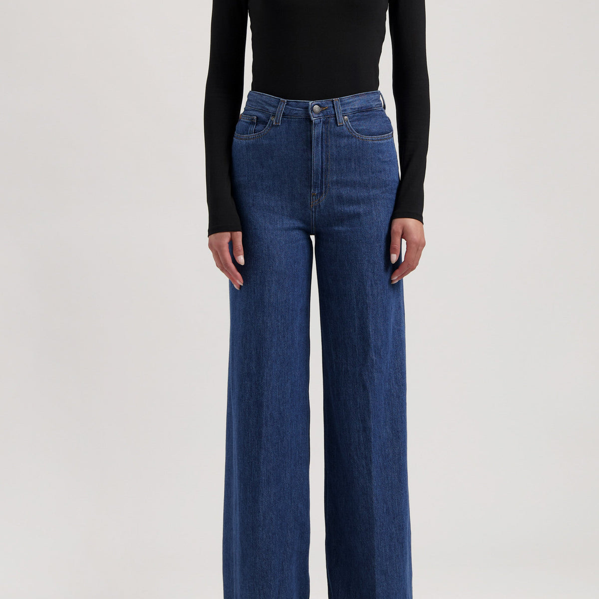 A stylish outfit featuring high-waisted, wide-leg blue jeans paired with a fitted, long-sleeve black top.