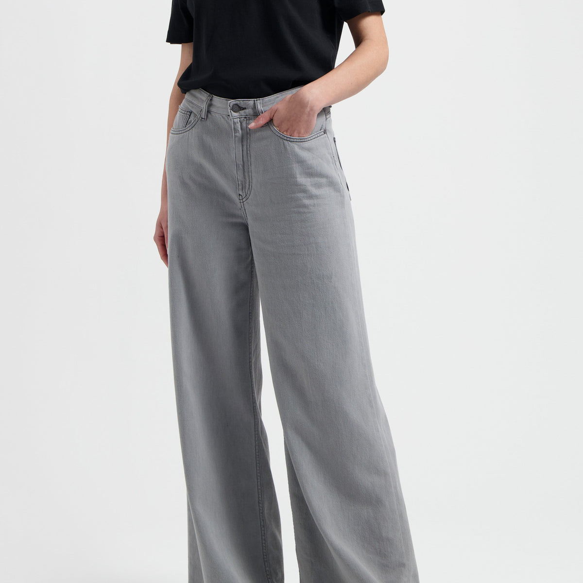 Model wearing a black slogan t-shirt and light gray wide-leg jeans, showcasing casual chic fashion style.