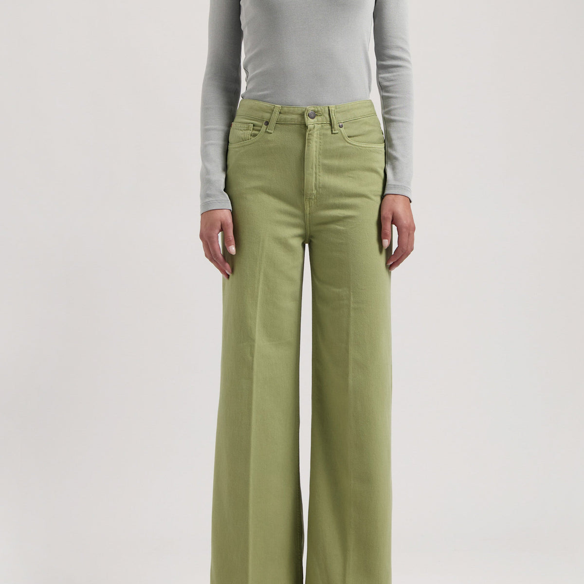 Light gray long-sleeve fitted top paired with wide-leg light green pants, worn with white pointed-toe shoes.