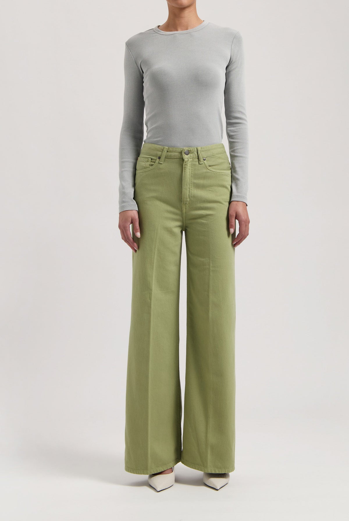 Light gray long-sleeve fitted top paired with wide-leg light green pants, worn with white pointed-toe shoes.