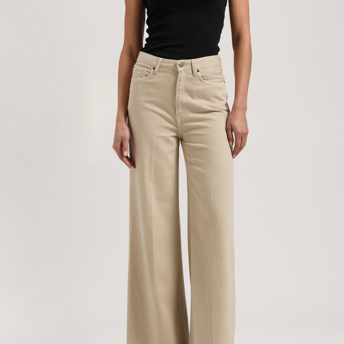 Wide-legged beige trousers paired with a black one-shoulder top, showcasing an elegant and modern look.