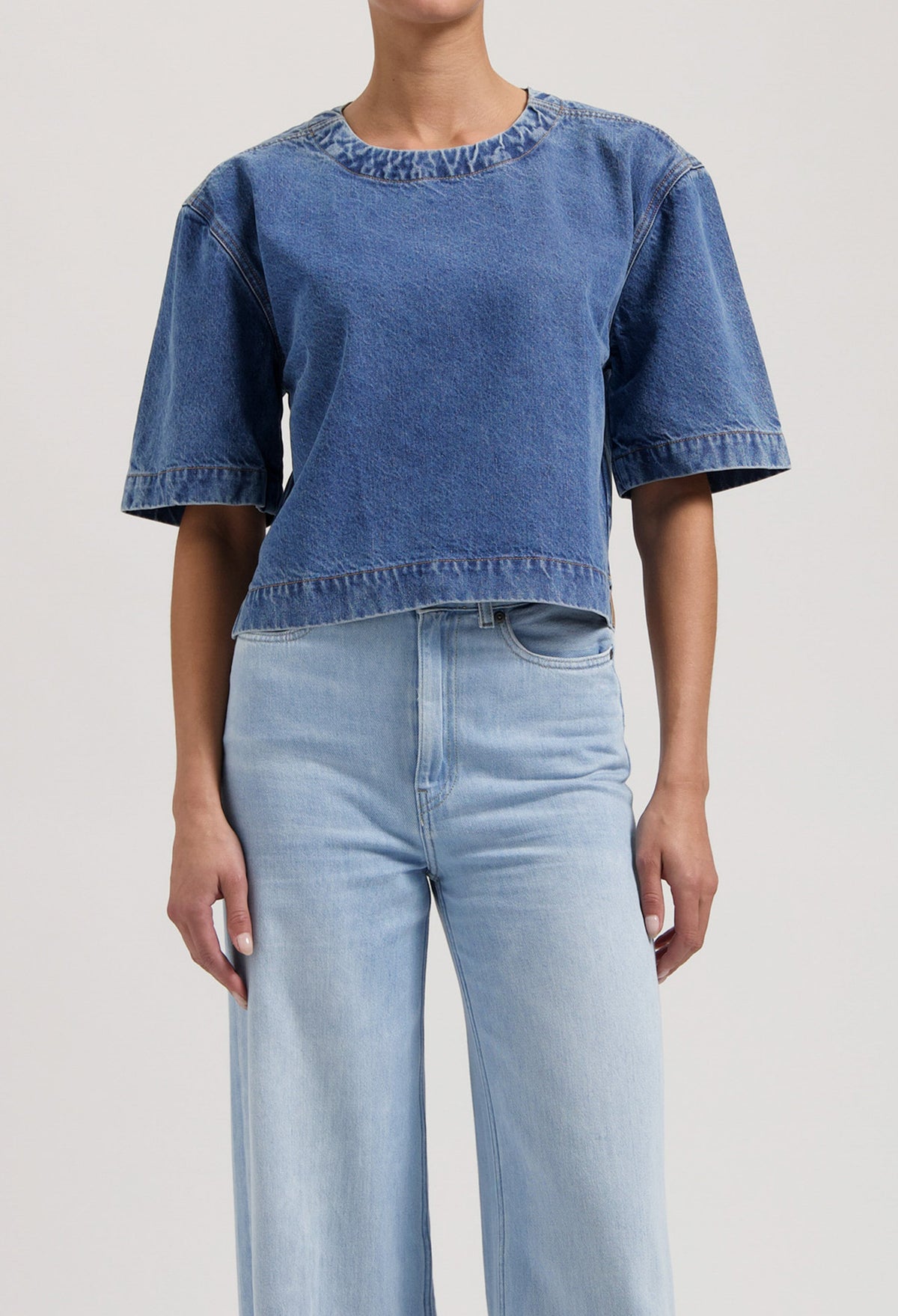 Casual outfit featuring a blue denim short-sleeve top paired with high-waisted light blue wide-leg jeans.