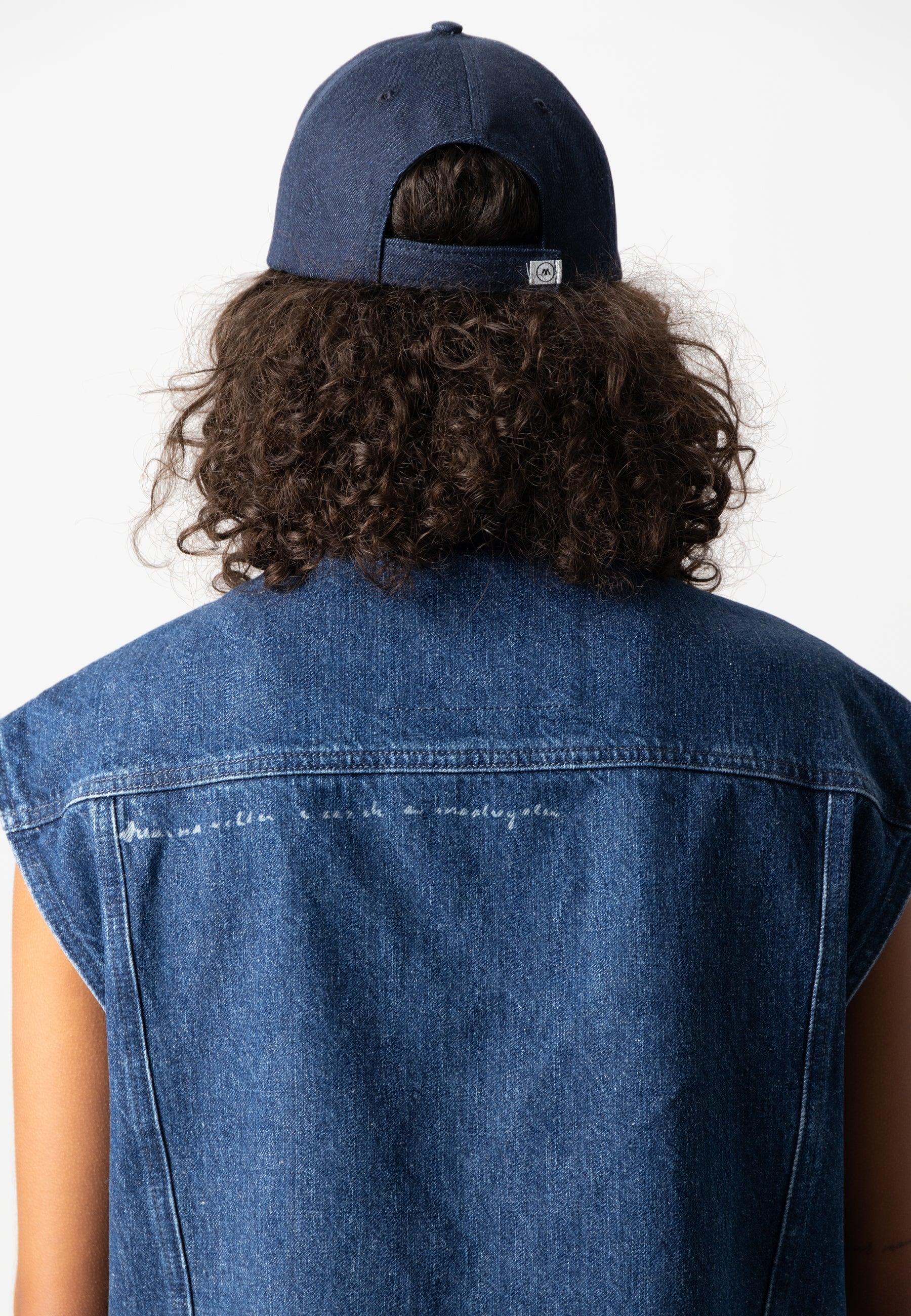 Sustainable Mud Jeans in deep blue denim overalls, paired with a white hoodie, embodying ethical fashion on stairs.