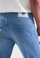 Sustainable MUD Jeans in dark denim, crafted for ethical fashion, featuring a straight fit and paired with sneakers.