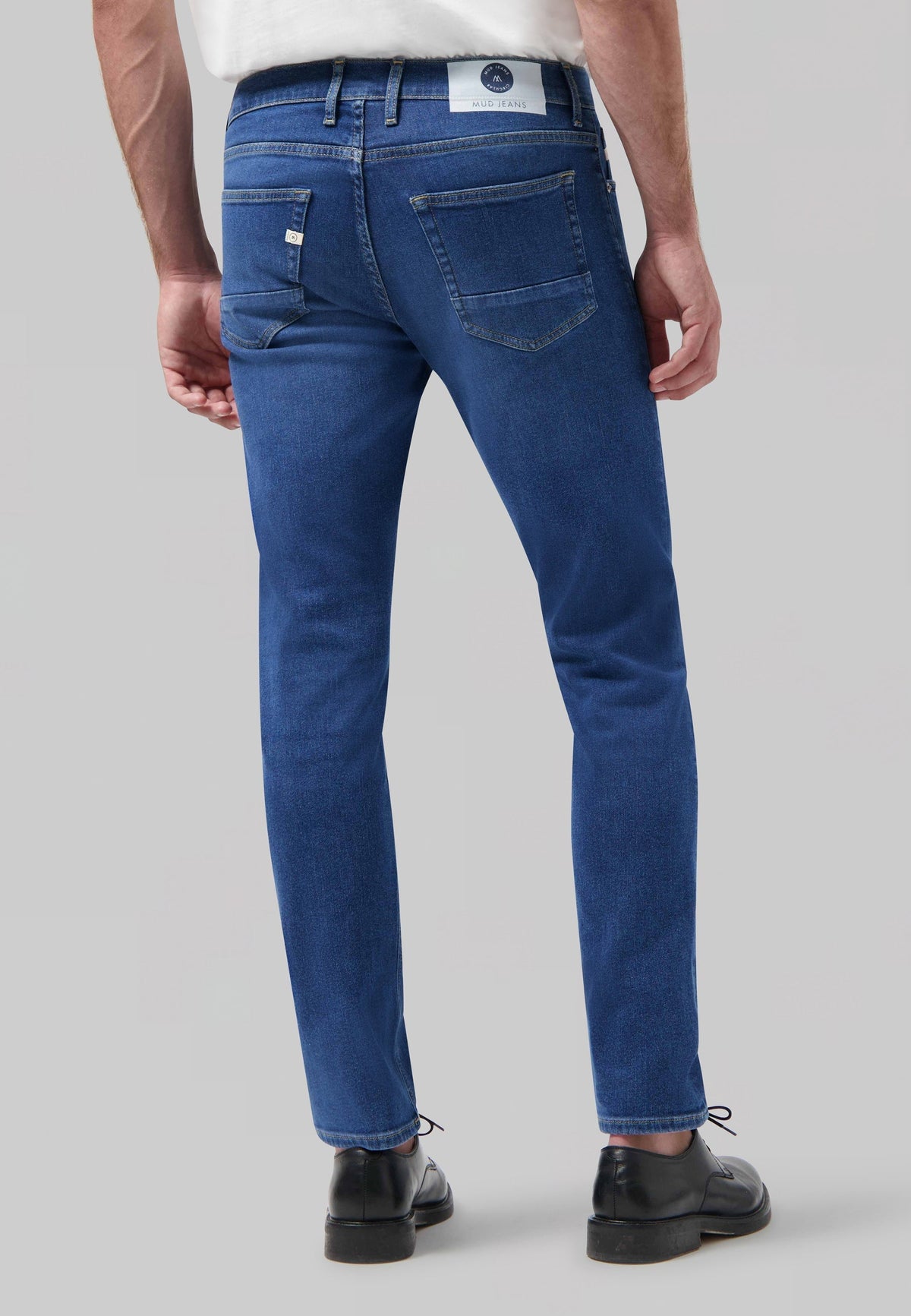Sustainable MUD Jeans denim shirt in light blue, crafted ethically, worn with dark jeans.